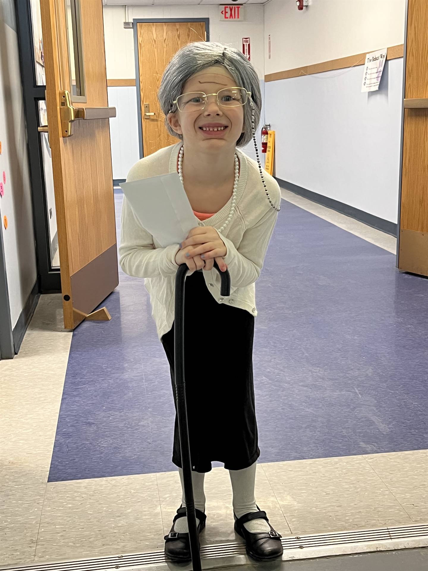 a student leans on a cane dressed as 100 years old