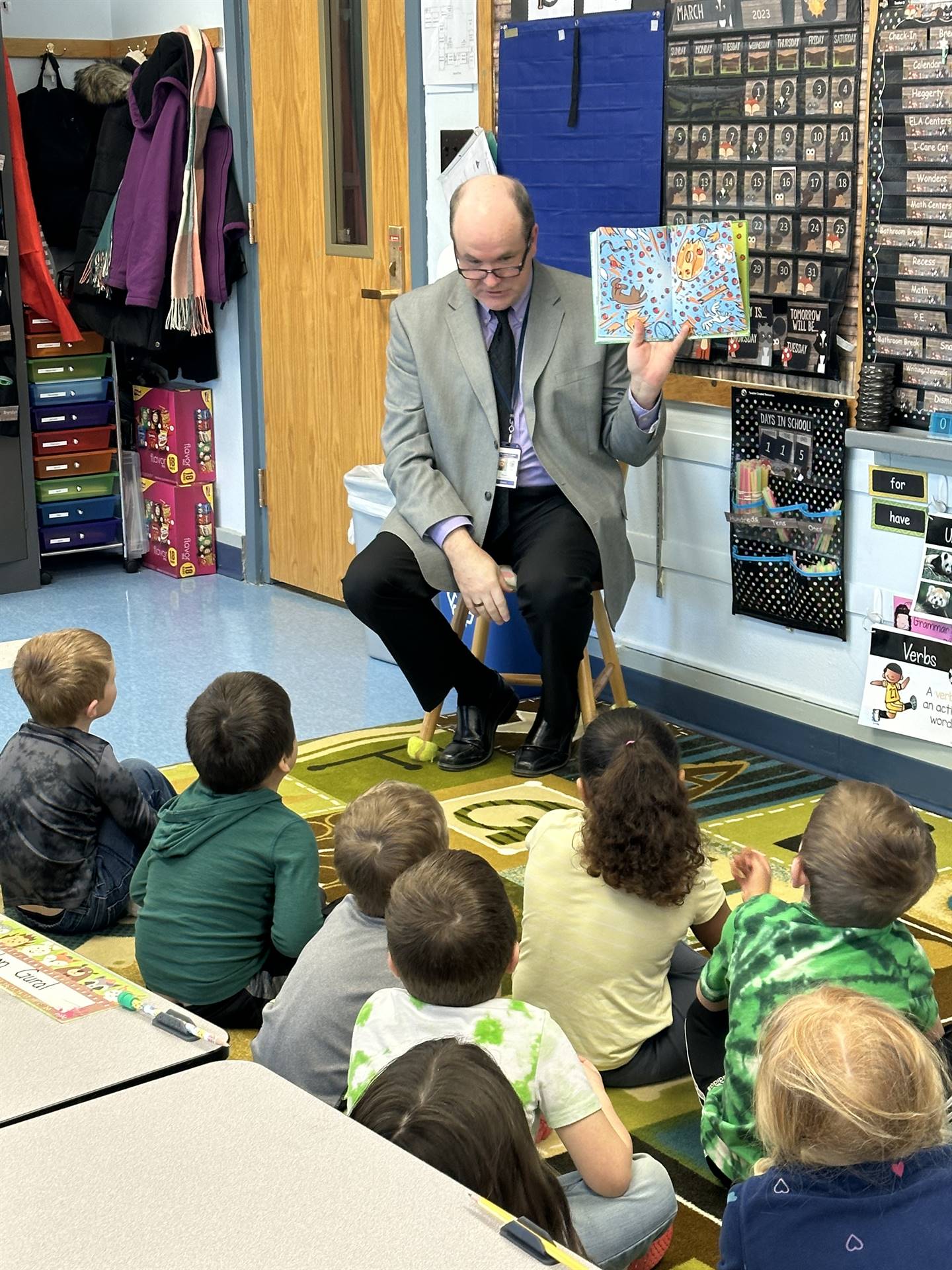 an adult reads a story to students
