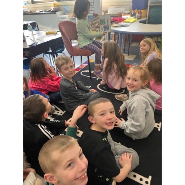 students listening to another student read a story.
