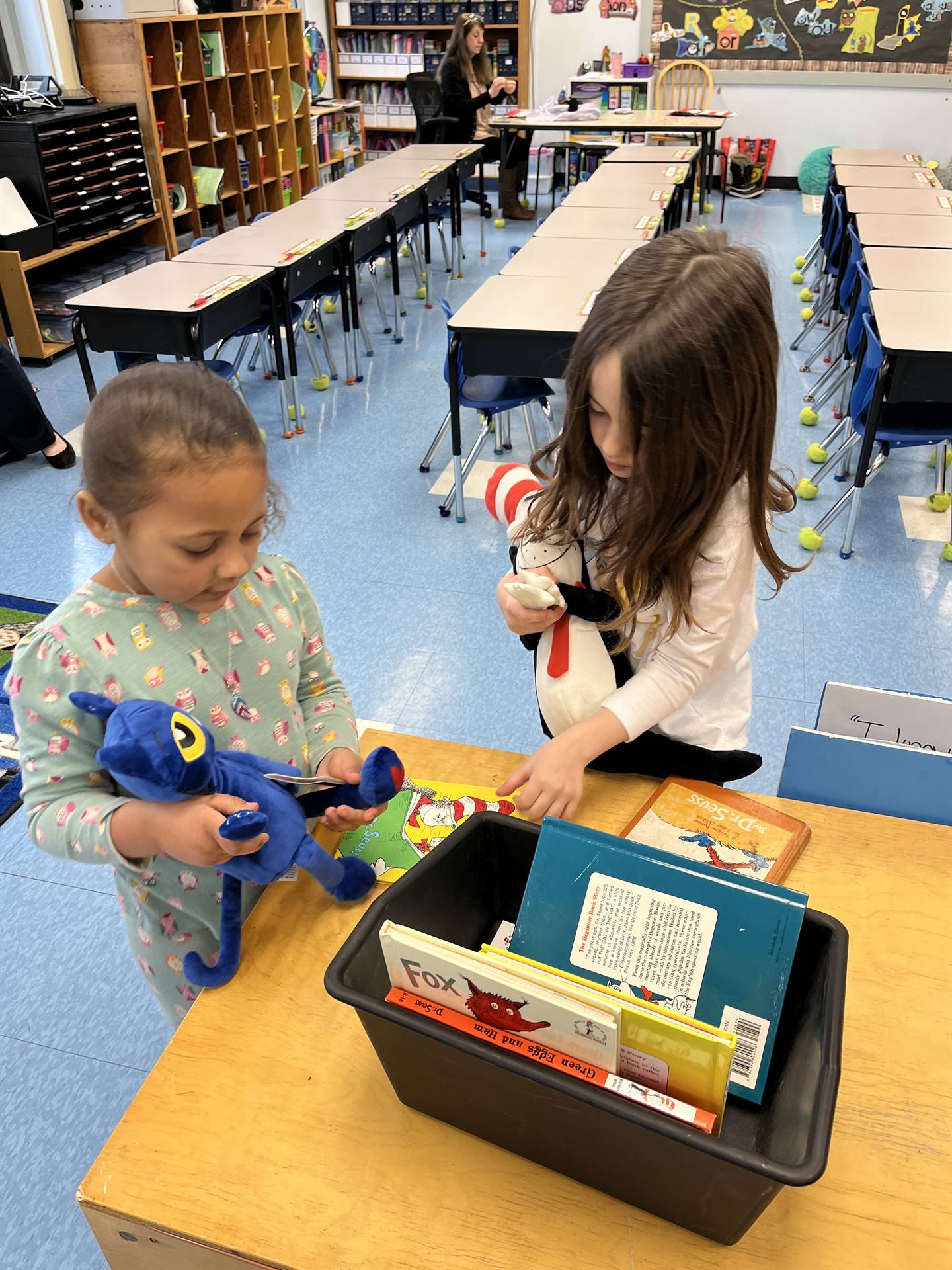 students holding stuffed animals search through books.