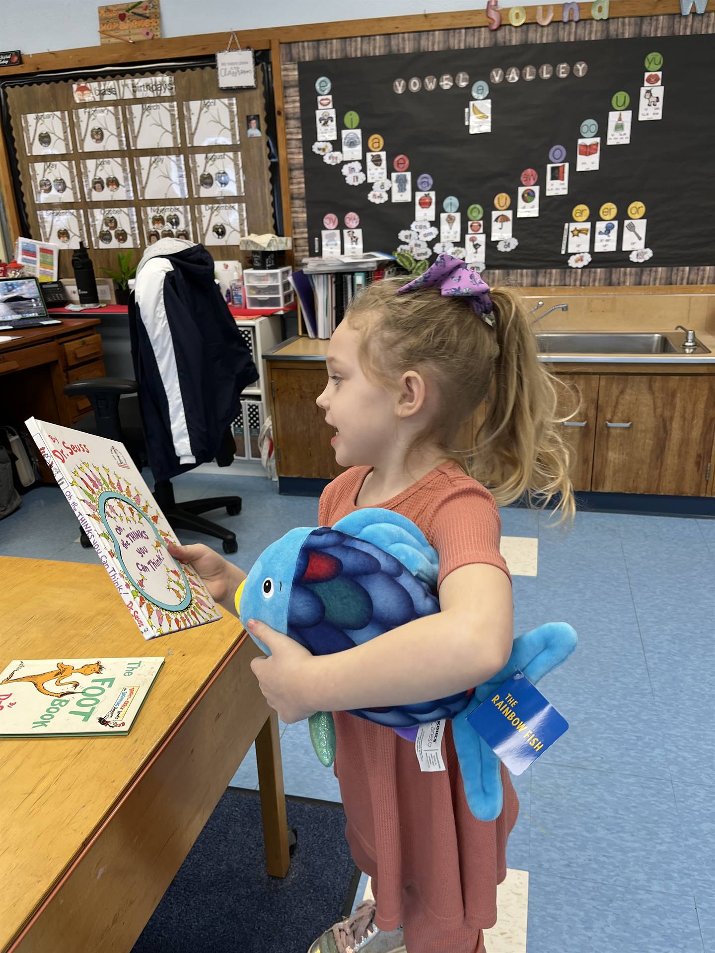 a student reading books to  stuffed animals.