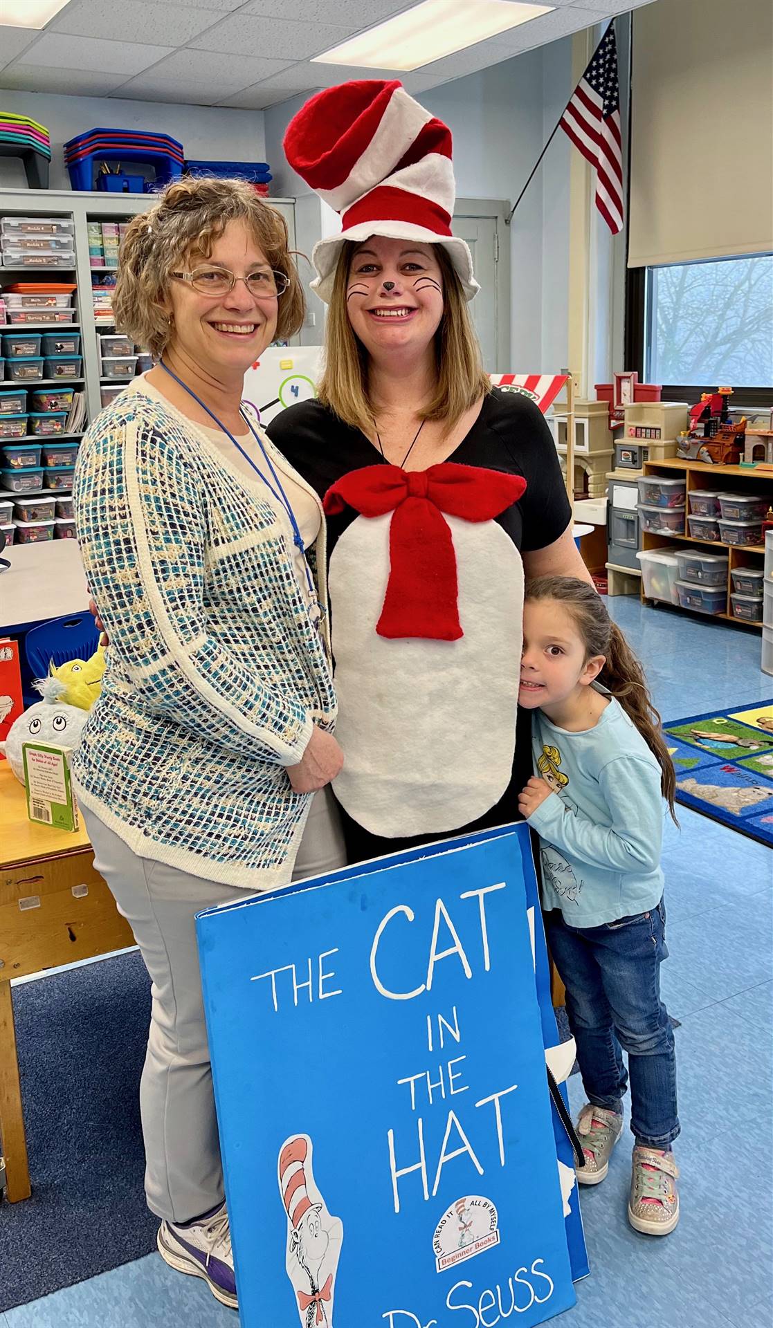 A staff member dressed in a cat in the hat character suit with another staff member and student.