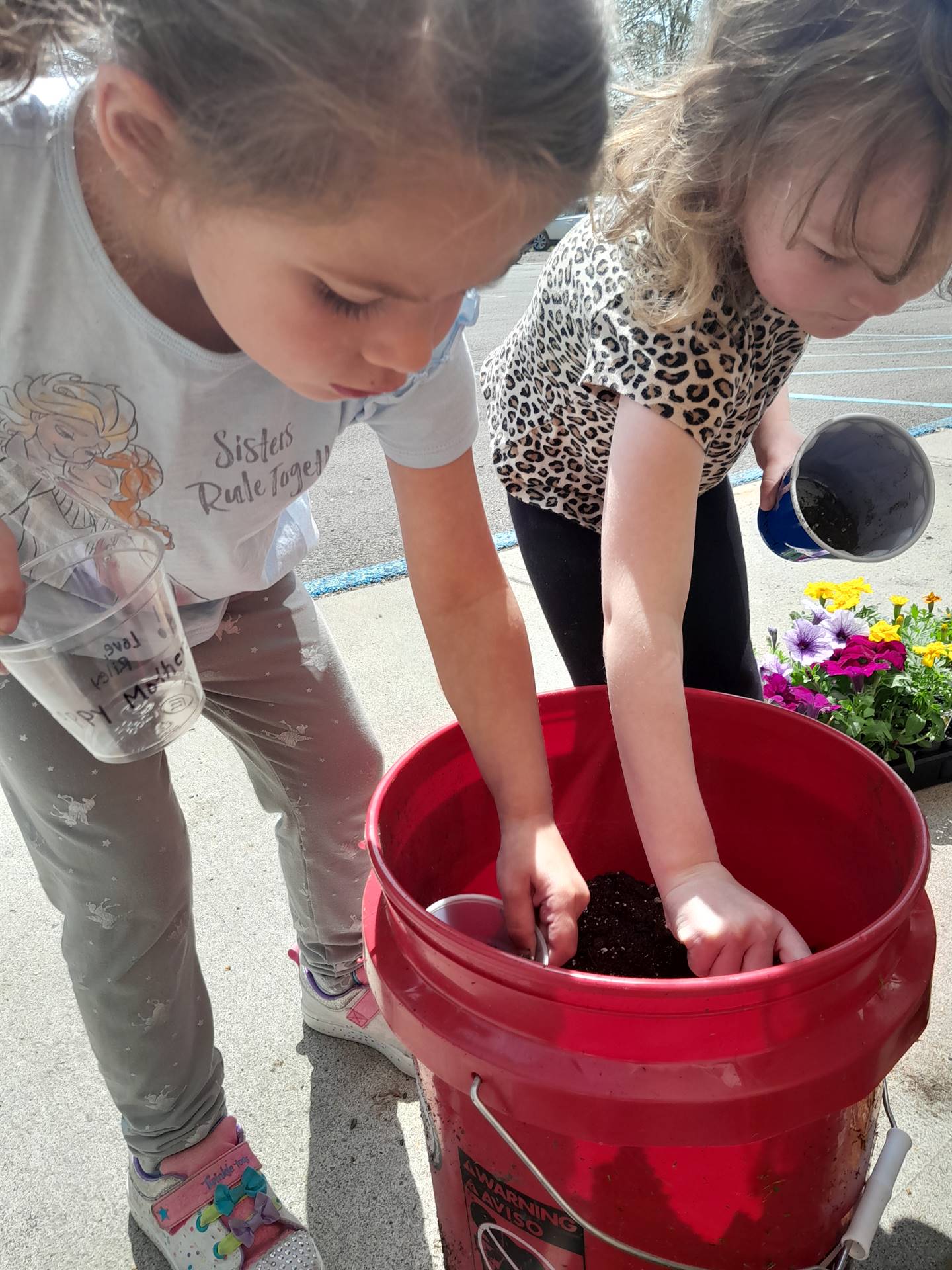2 students are digging soil from a bucket