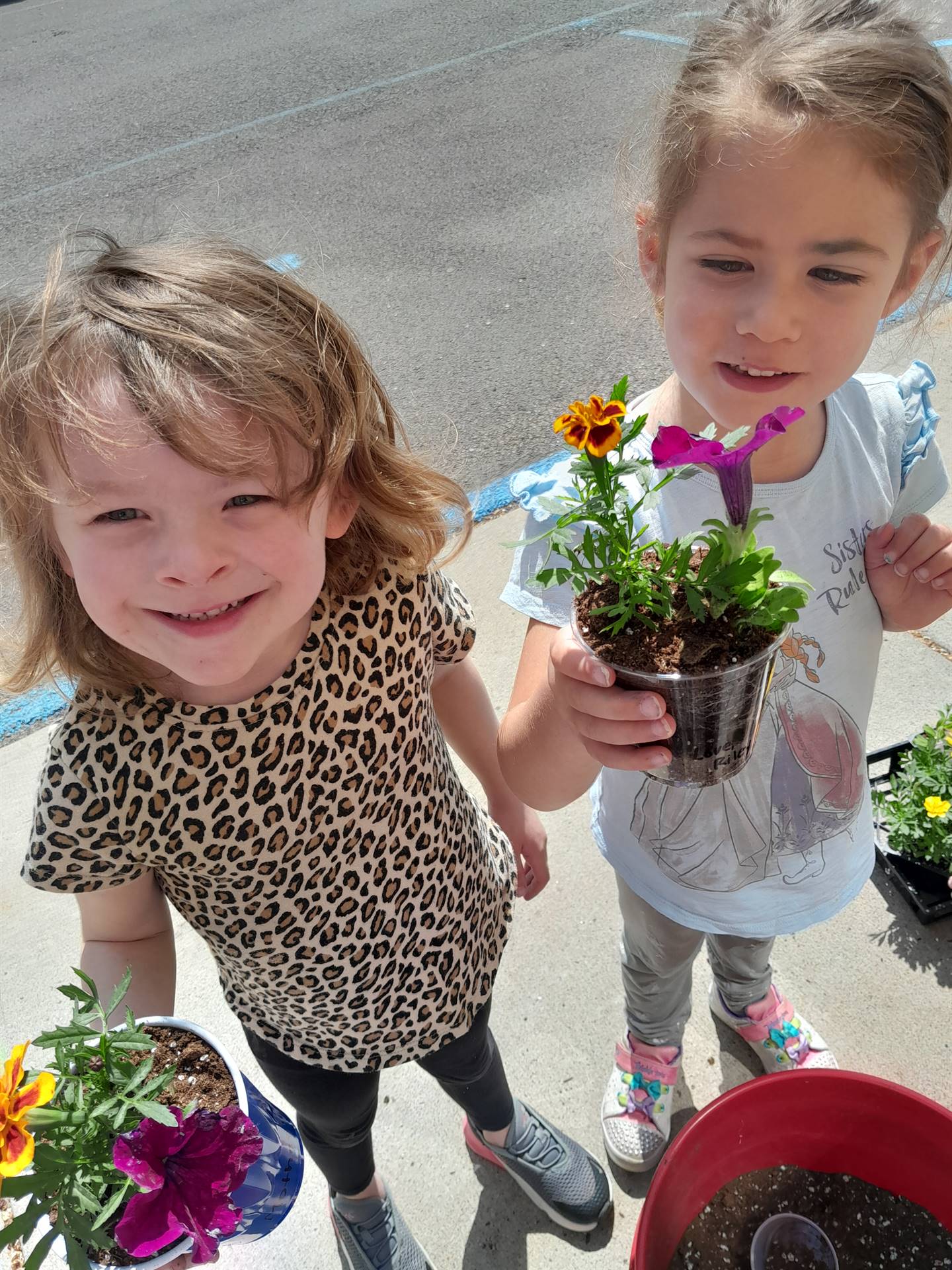 2 students hold up planted flowers
