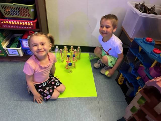 2 students sitting on floor with a cup stacking design