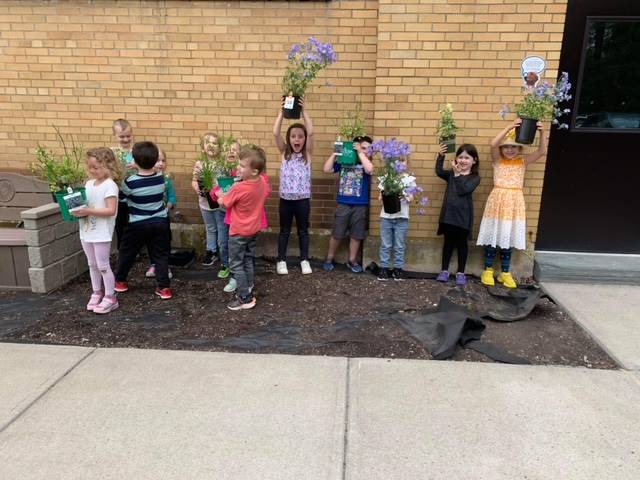 students outside holding up pots of flowers