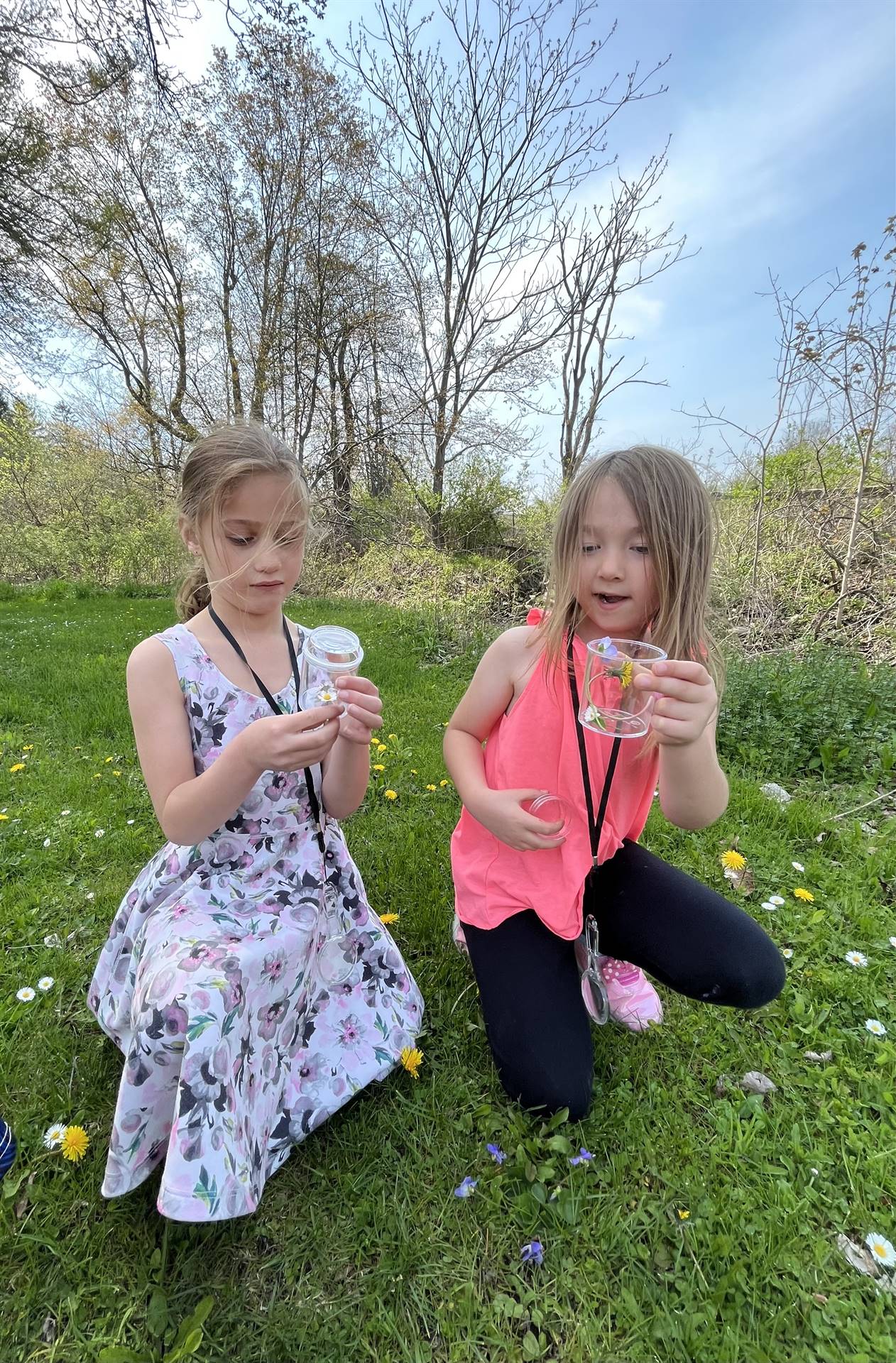 2 students looking at nature finds in their jars.