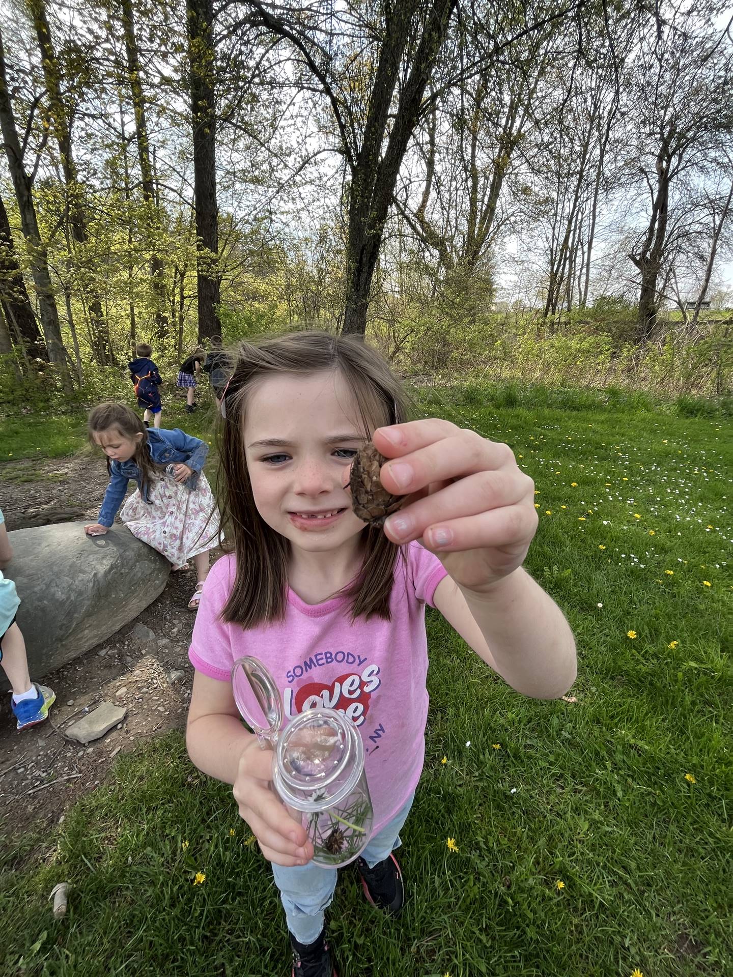 a student holds up a jar of nature items.