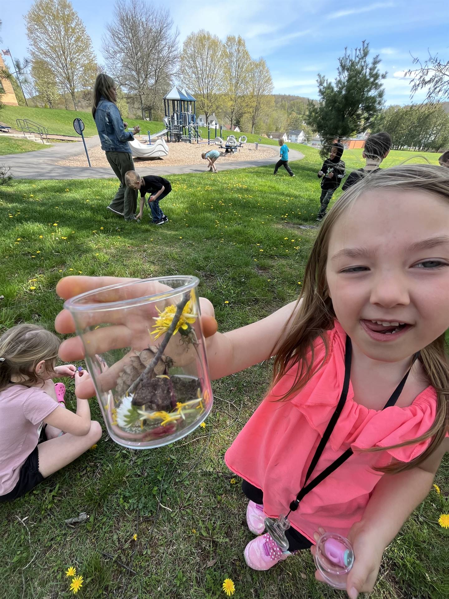 a student holds up a jar of nature items