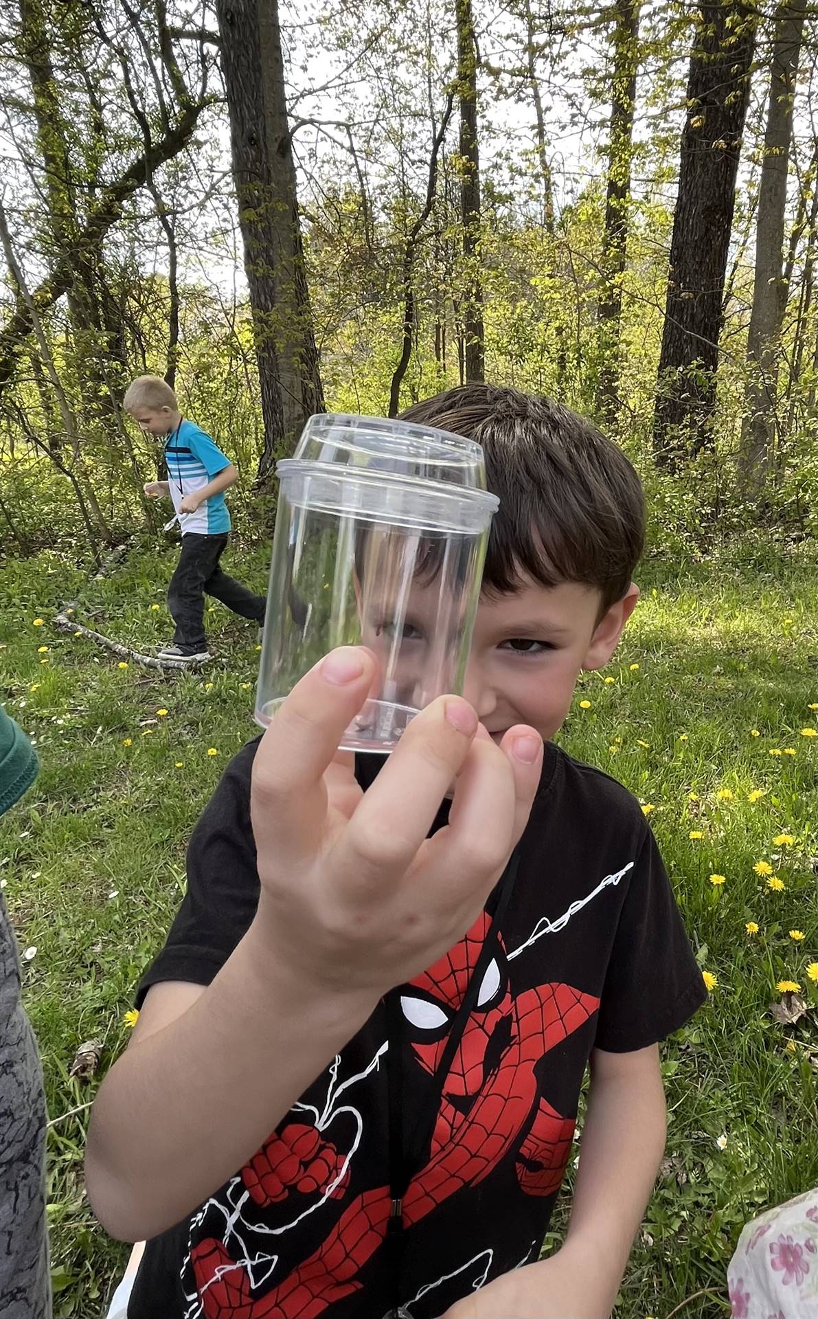 a student holds up a jar of nature items