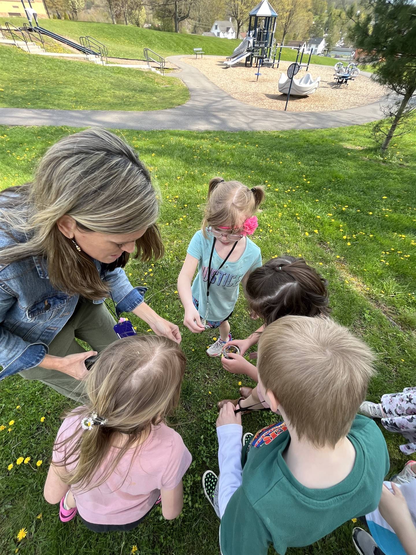 students and a staff member looking through magnifying glasses outdoors