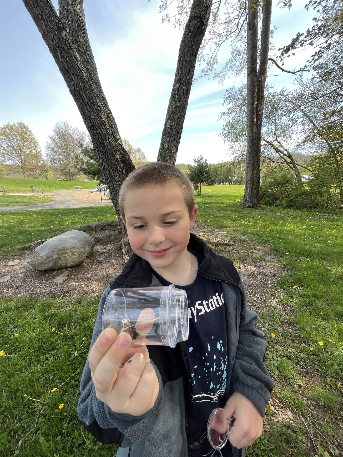 a student holds up a jar of nature items