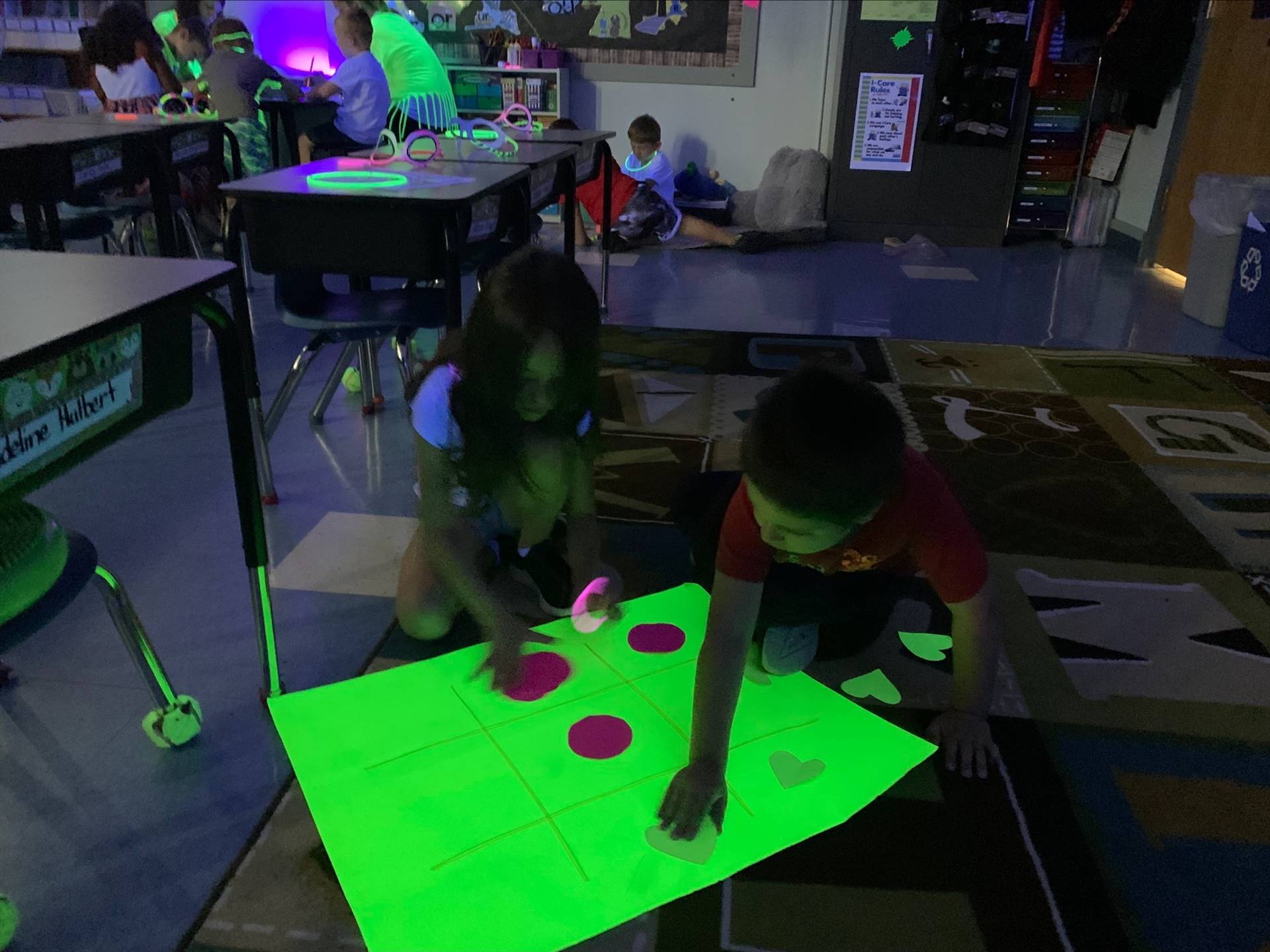 2 students playing on a neon game board