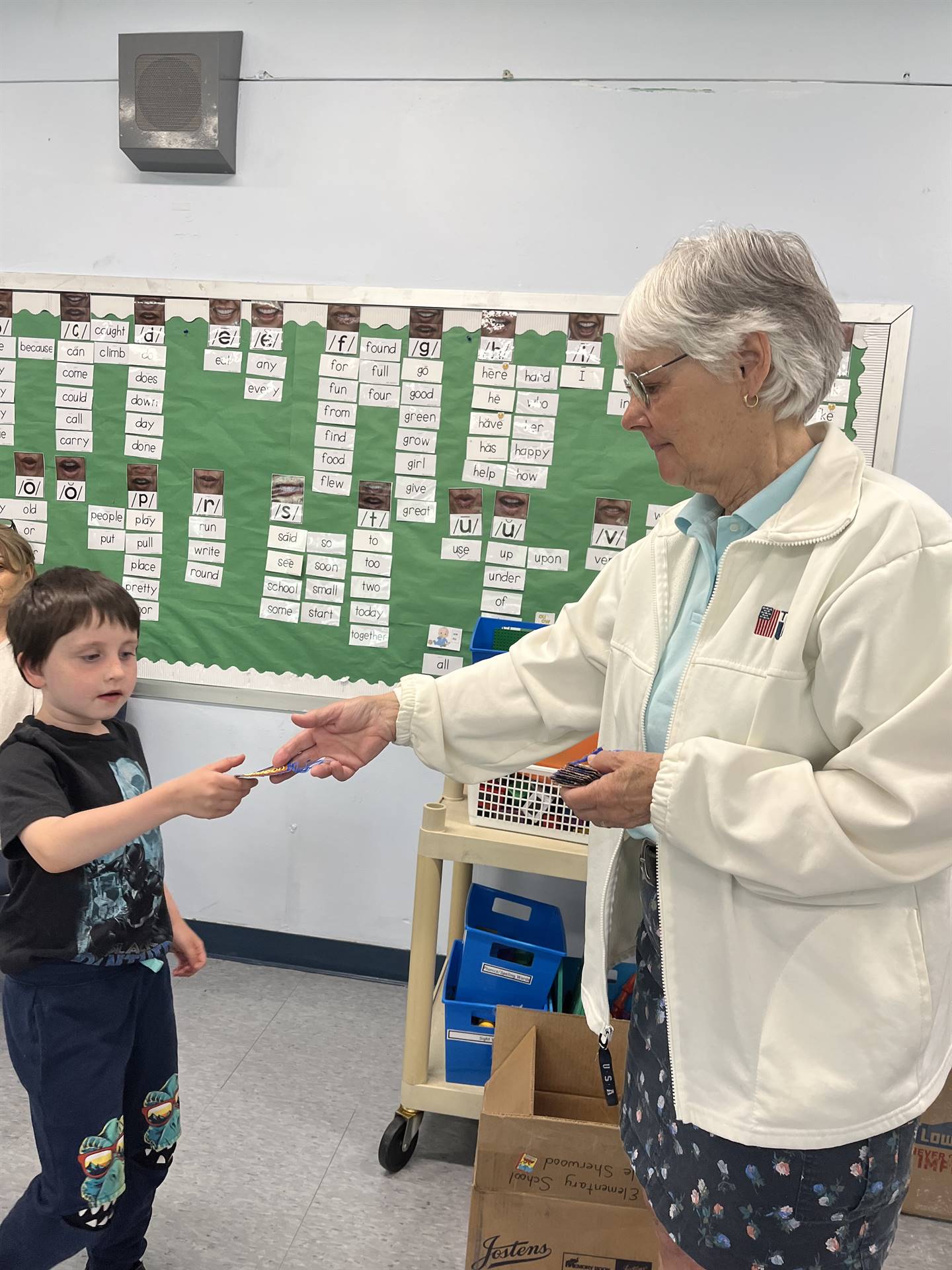 adult handing bookmark to student