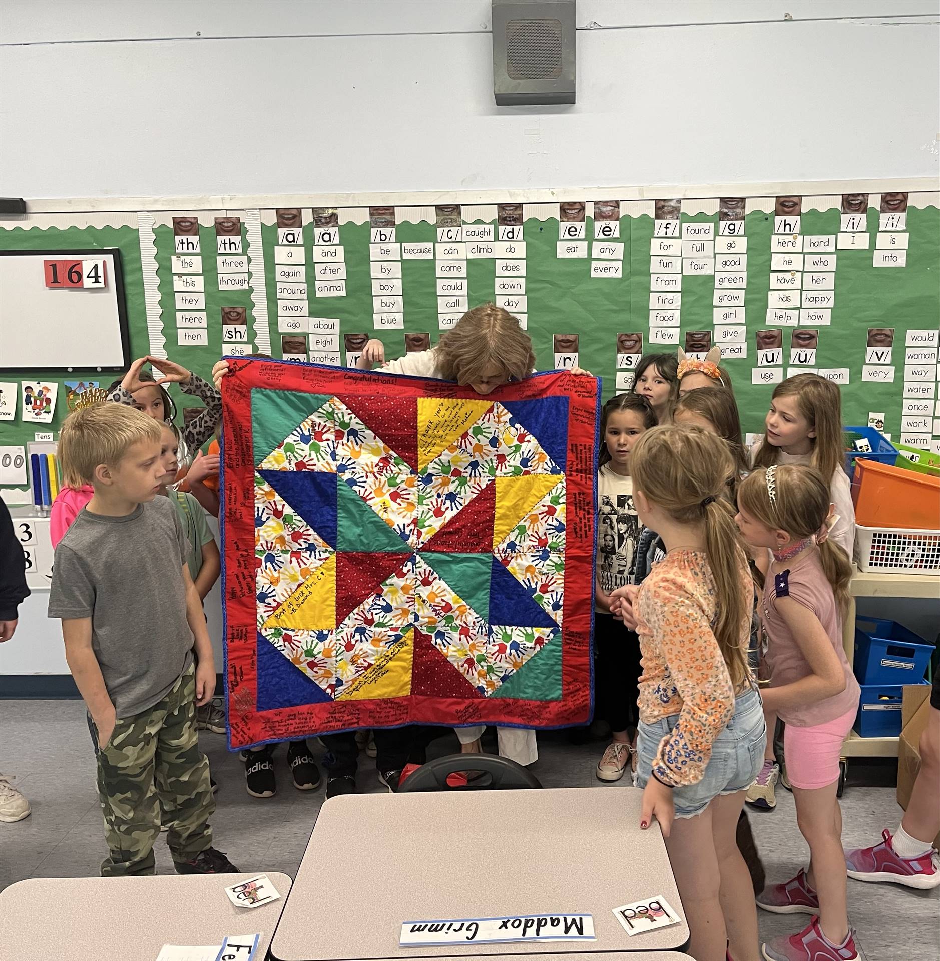 teacher with quilt and students around her