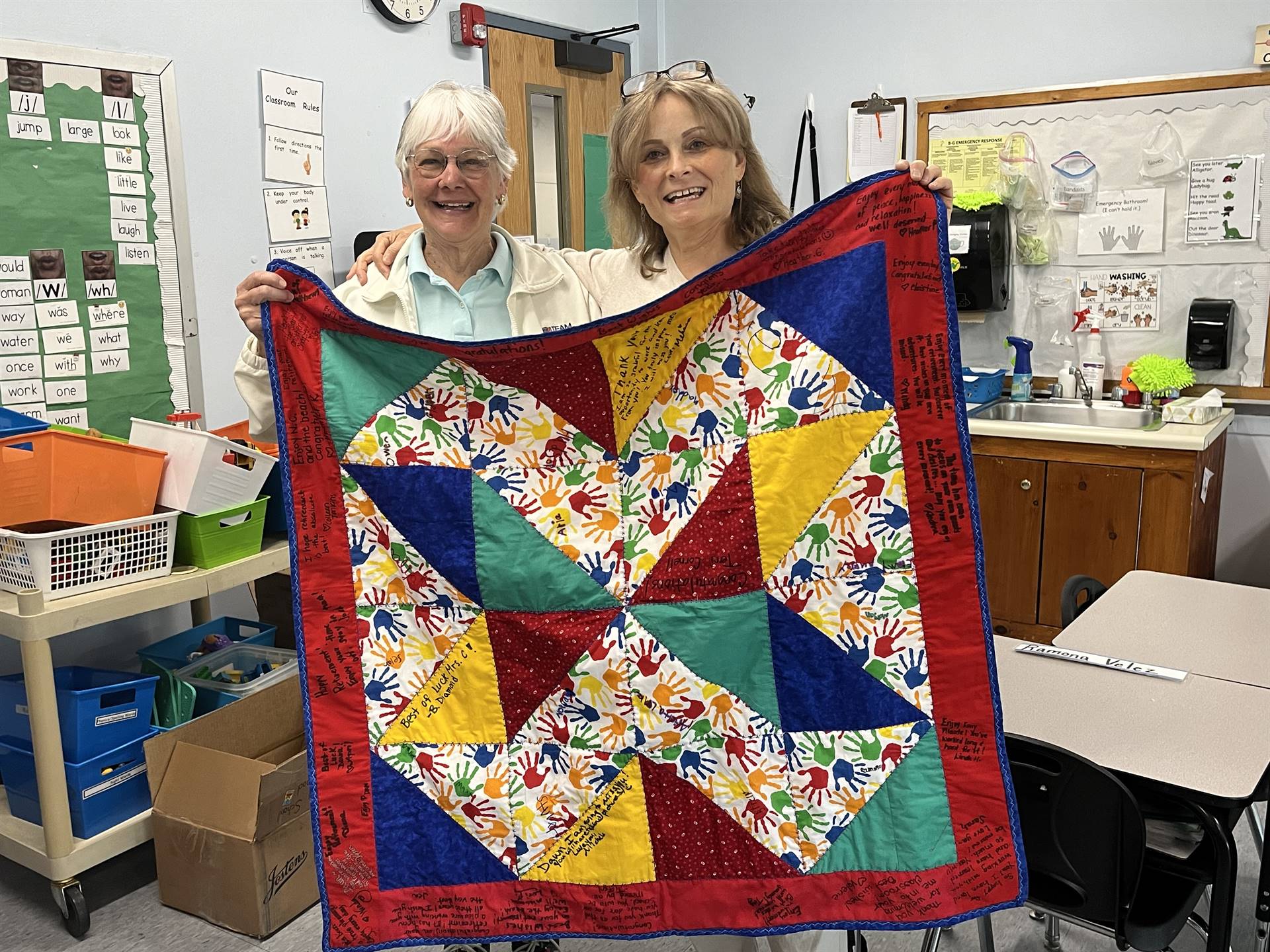 2 adults holding up quilt