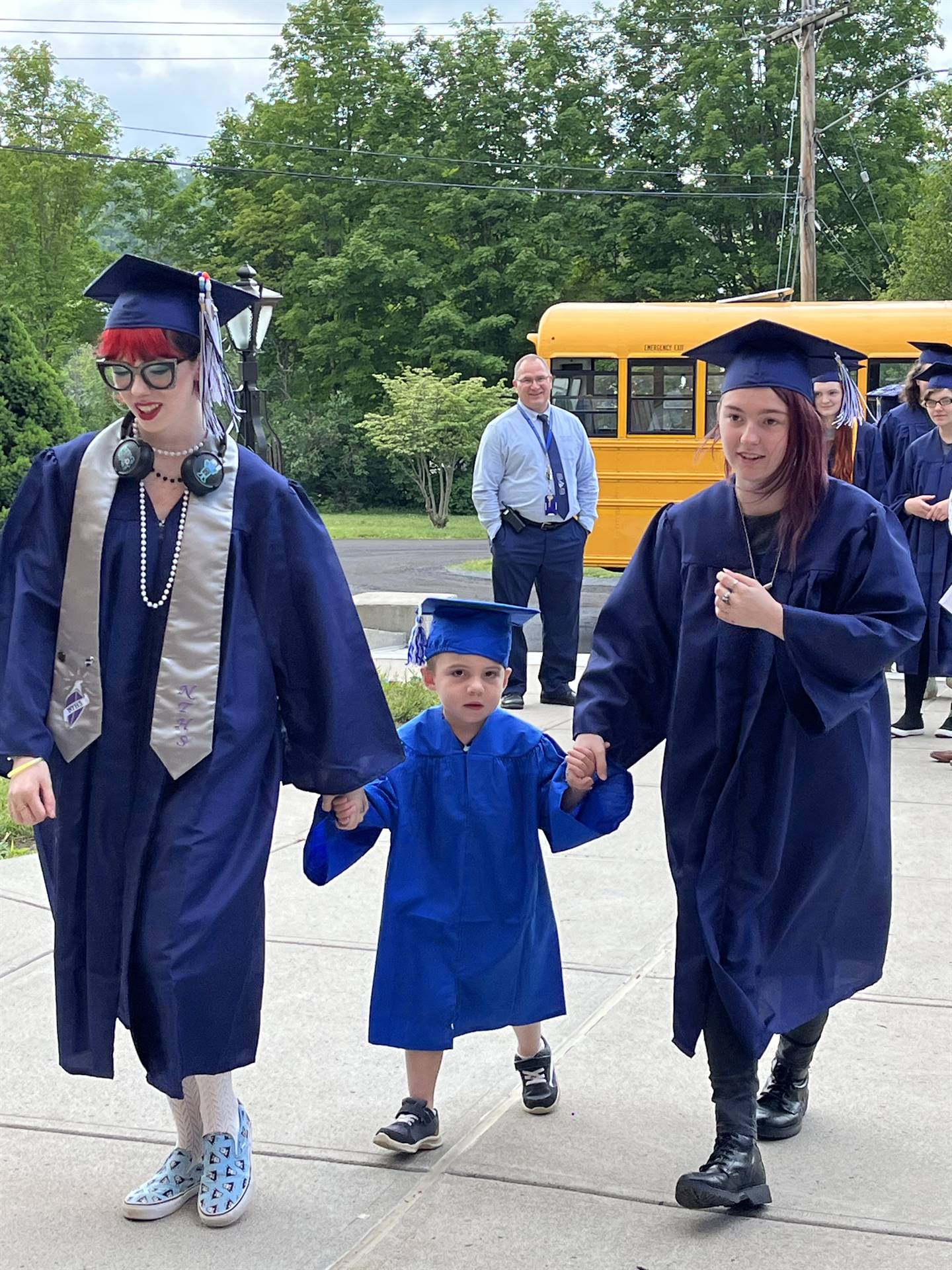 2 2023 senior graduates with a pre k student in middle dressed in caps and gowns