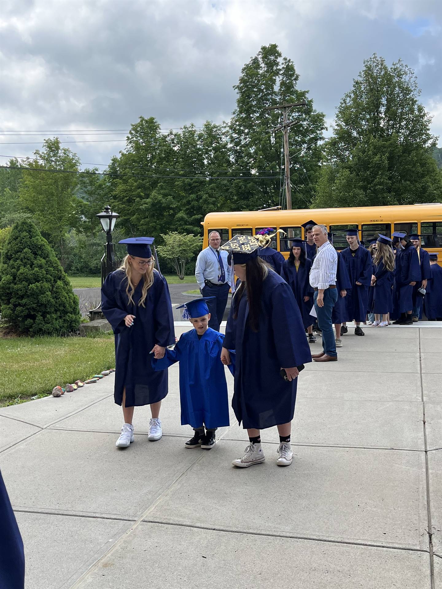 2 2023 senior graduates with a pre k student in middle dressed in caps and gowns