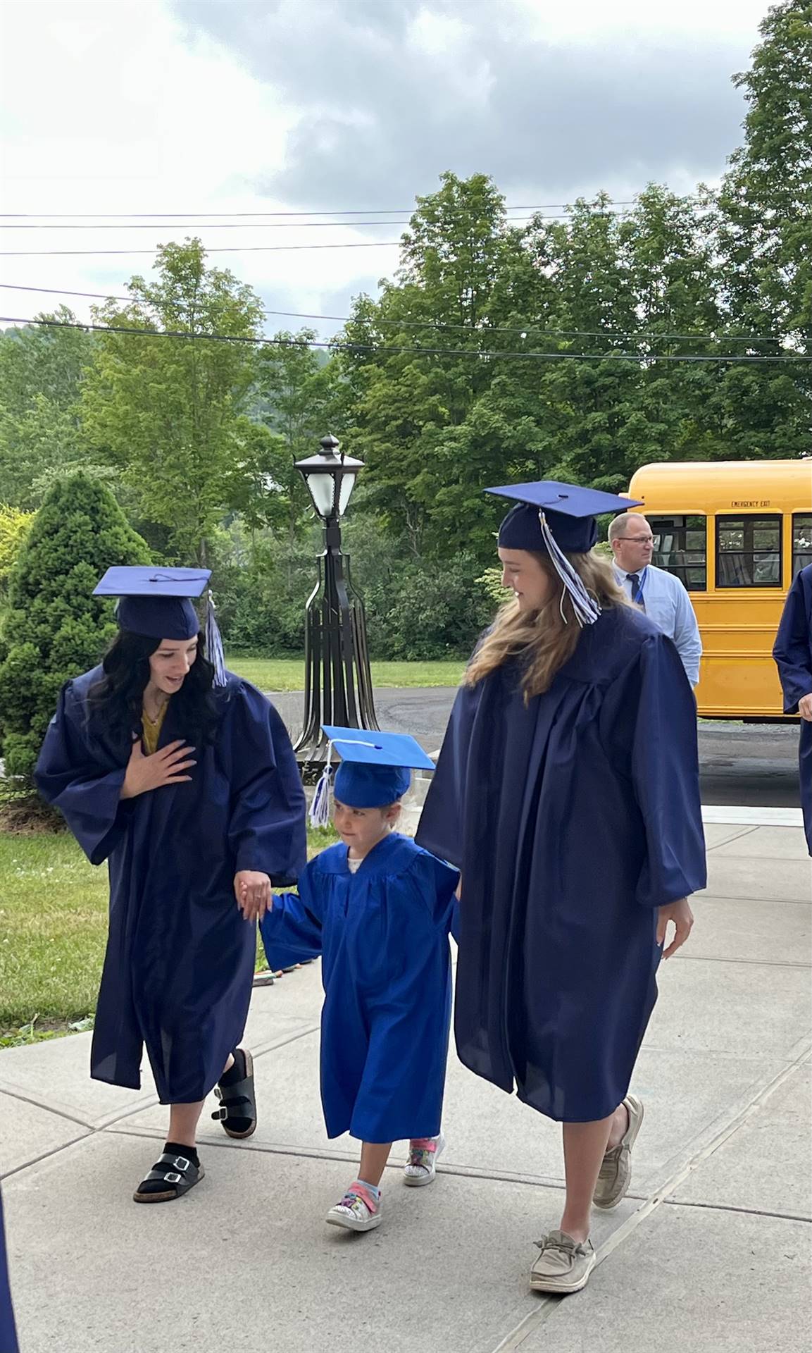 2 2023 senior graduates with a pre k student in middle dressed in caps and gowns