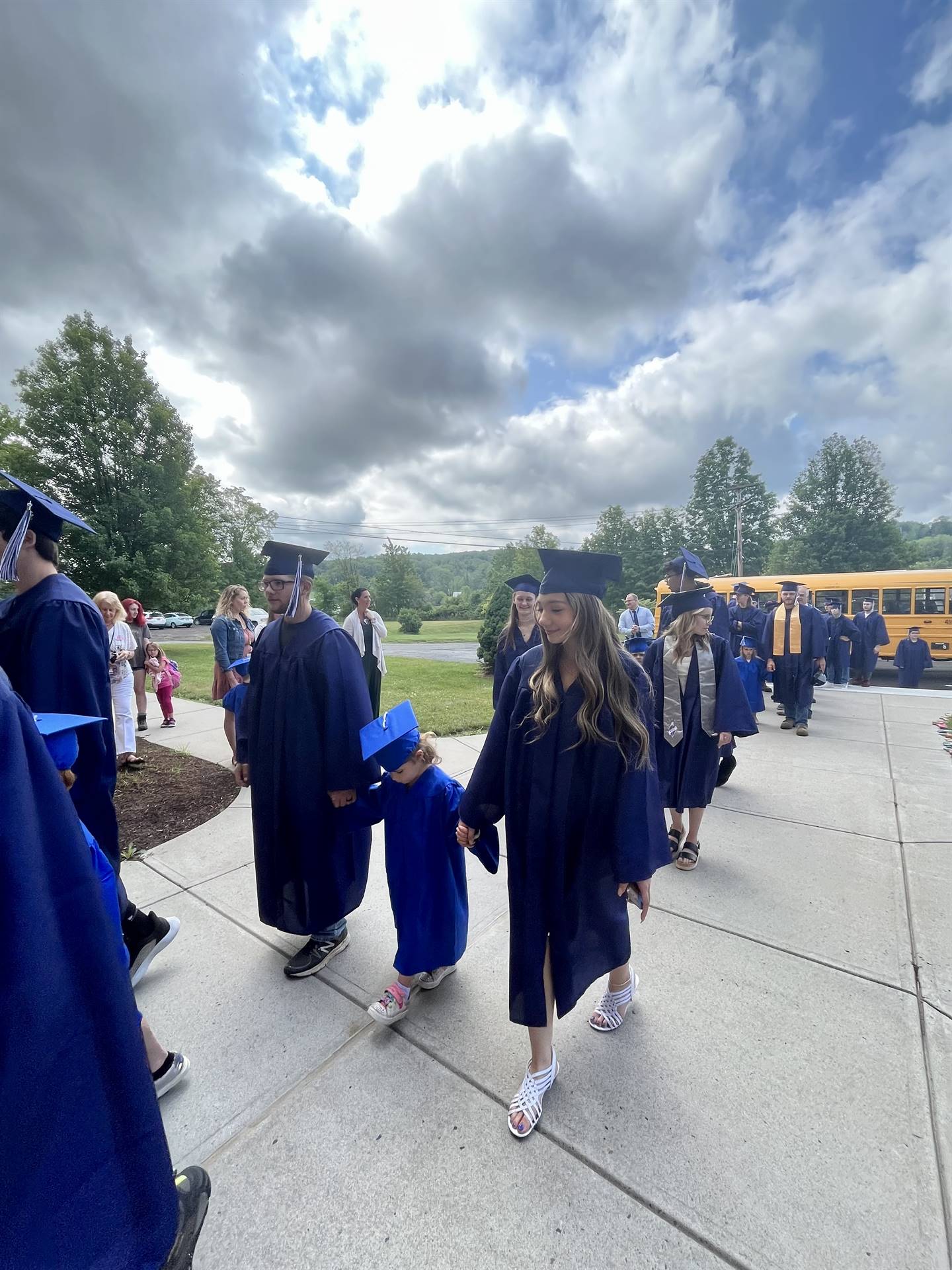 2 2023 senior graduates with a pre k student in middle dressed in caps and gowns