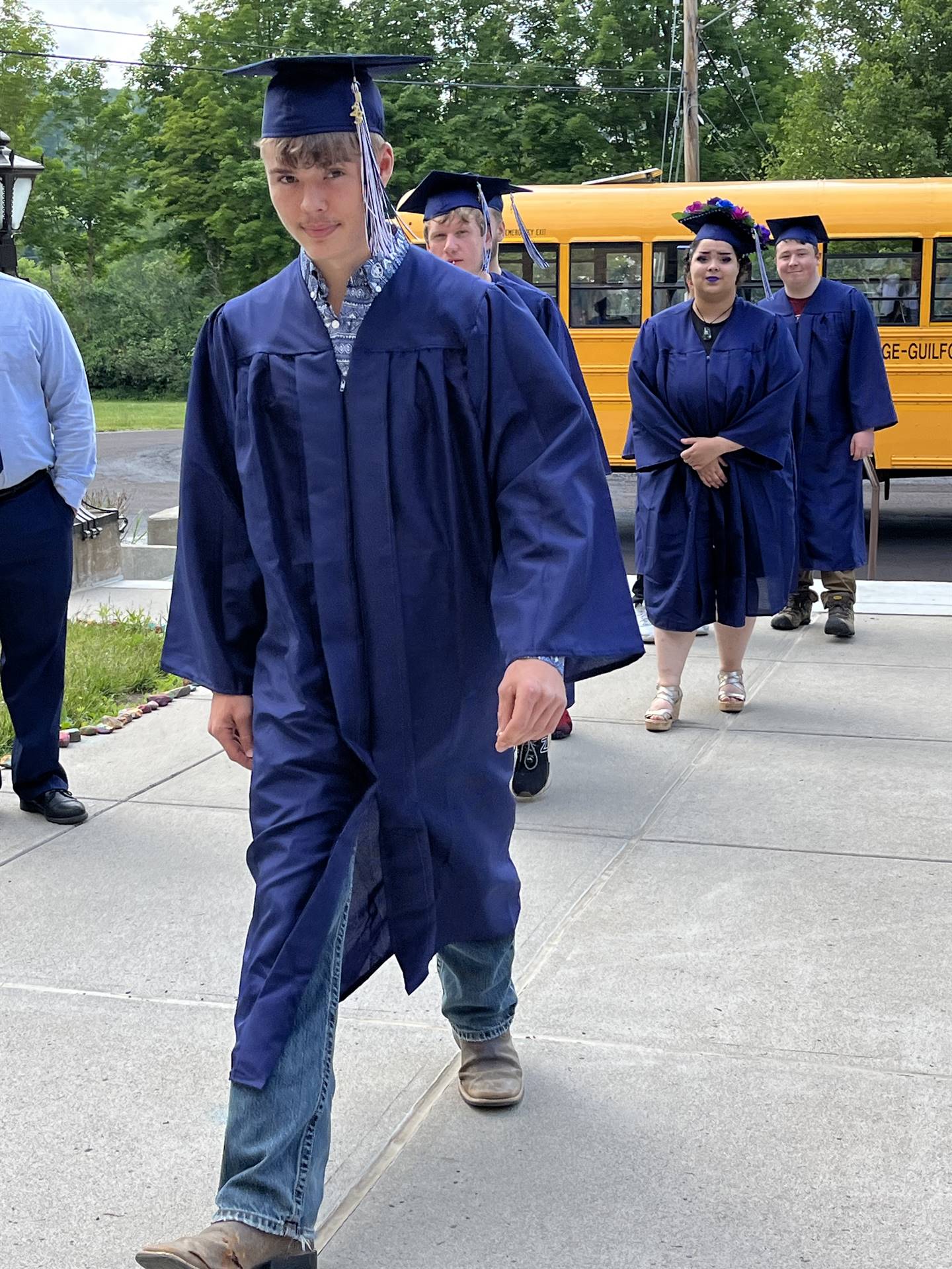 2 2023 senior graduates with a pre k student in middle dressed in caps and gowns