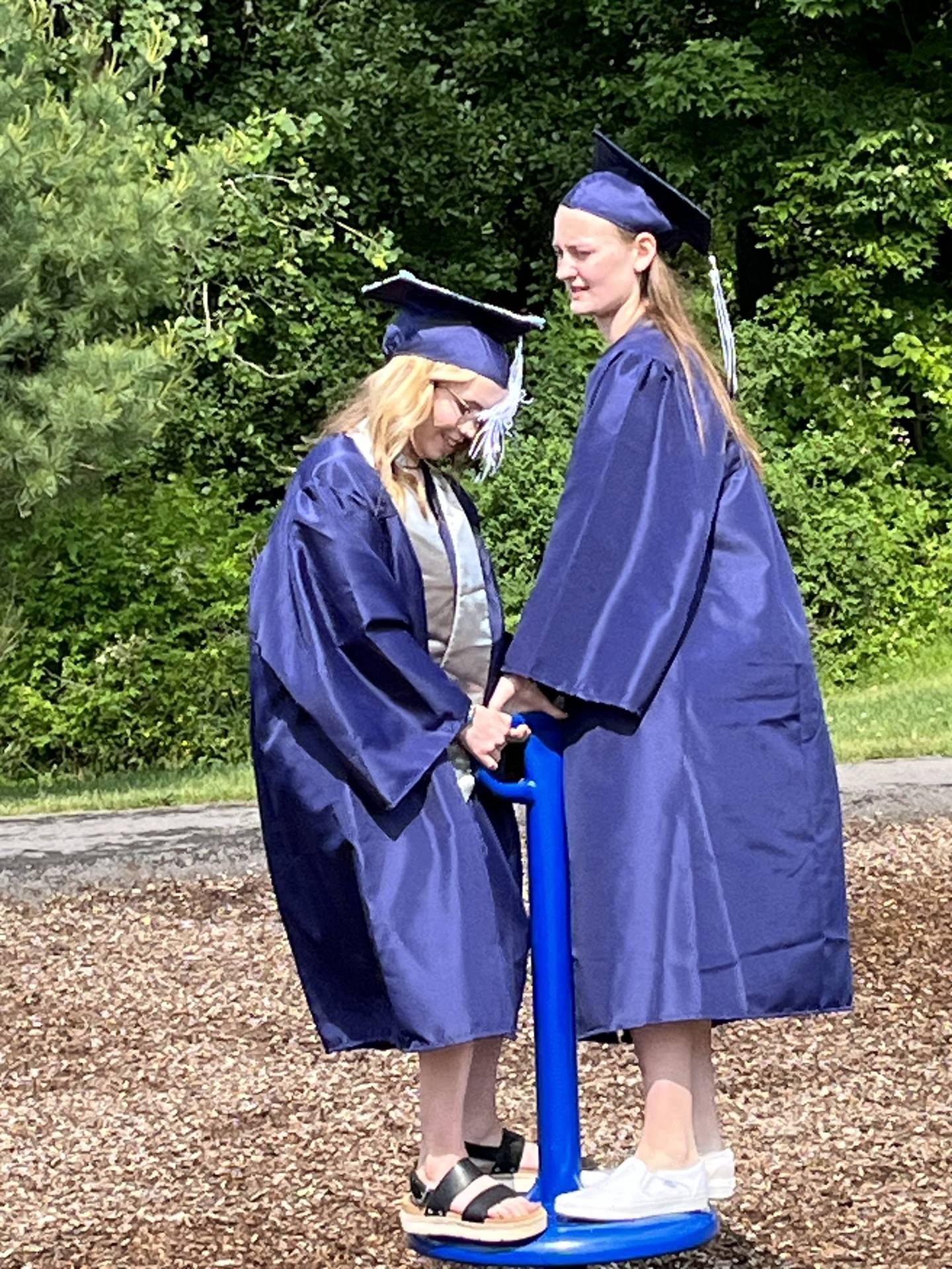 2 senior graduates on playground spinner