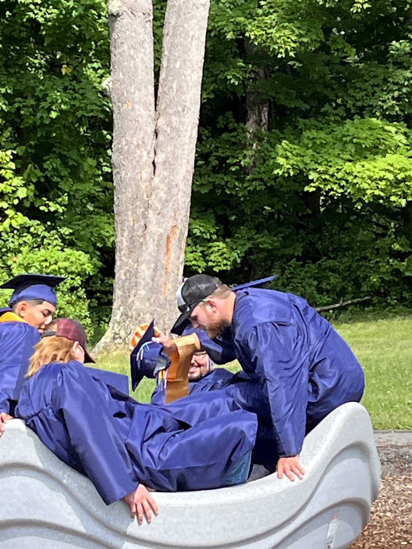 4 senior graduates on playground merry go round