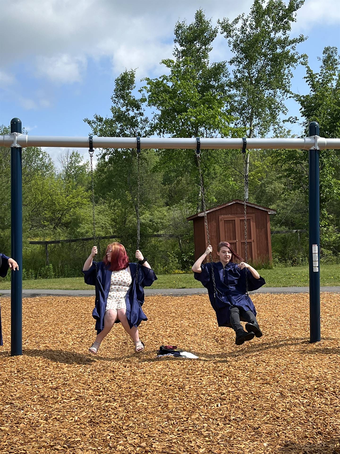 2 senior graduates on playground swings