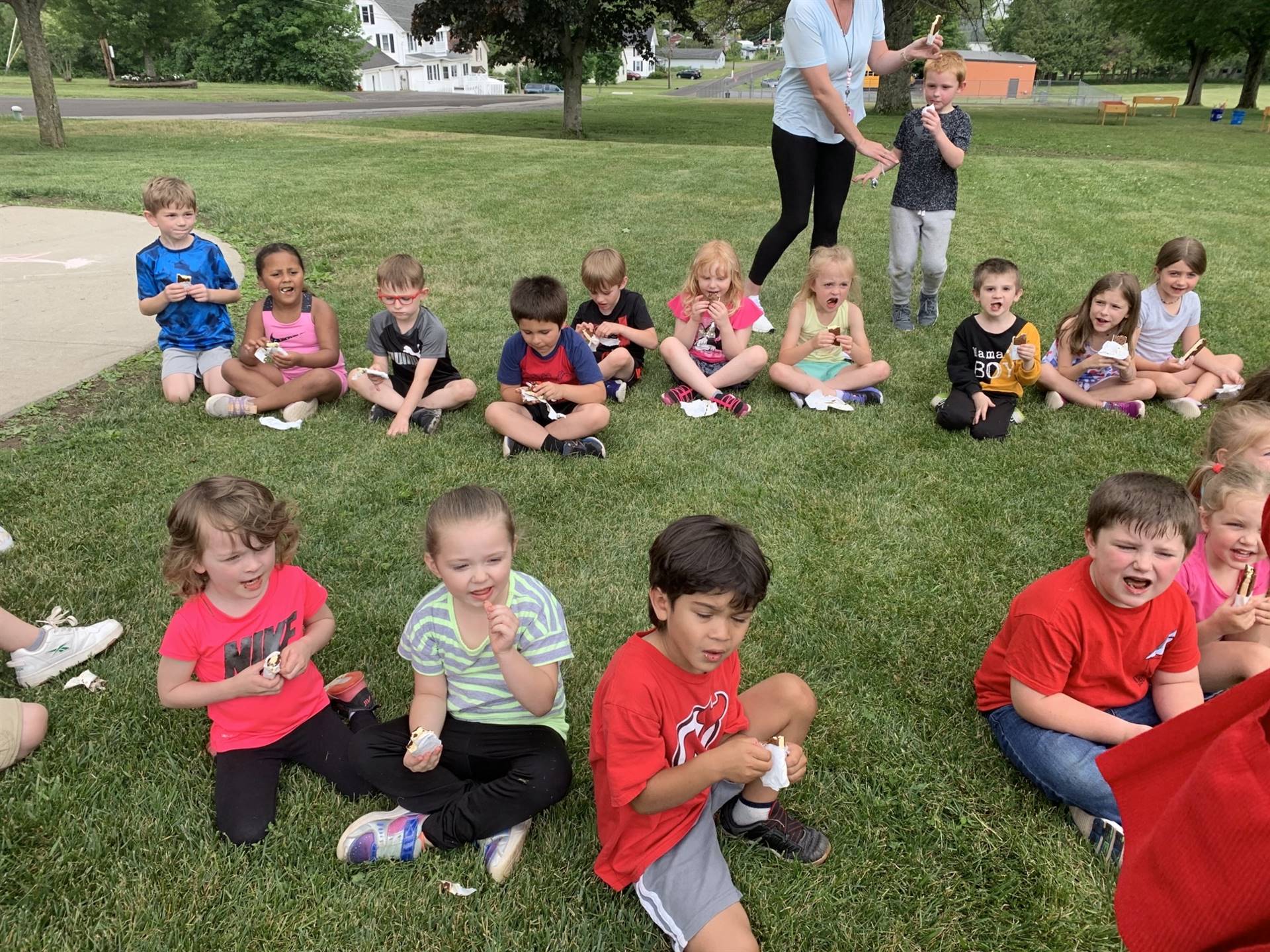 Children sitting on grass eating an ice cream treat