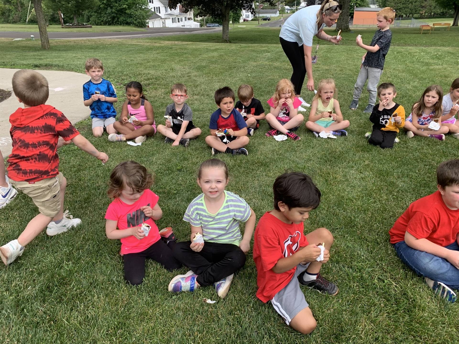 Children sitting on grass eating an ice cream treat