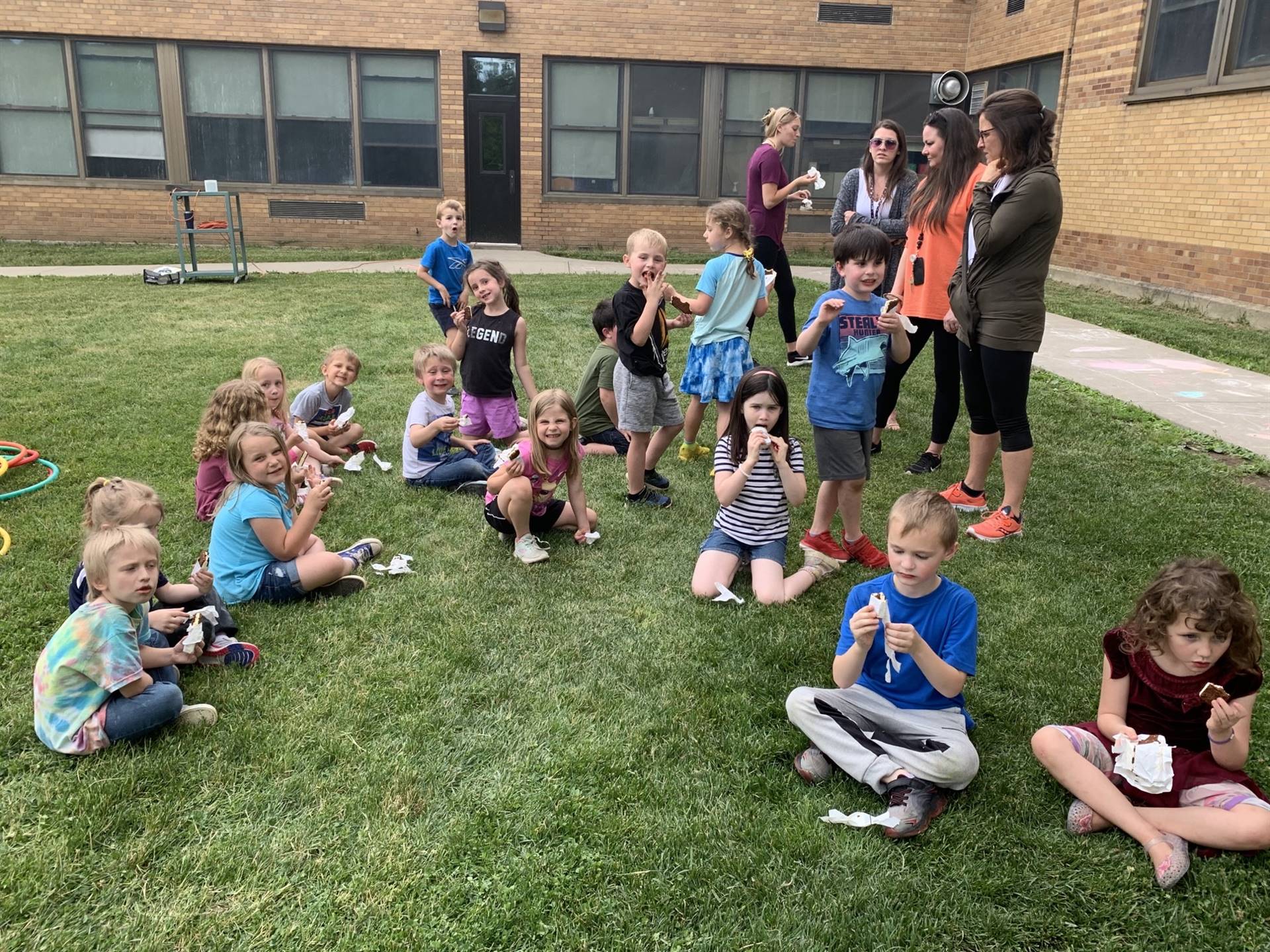 Children sitting on grass eating an ice cream treat