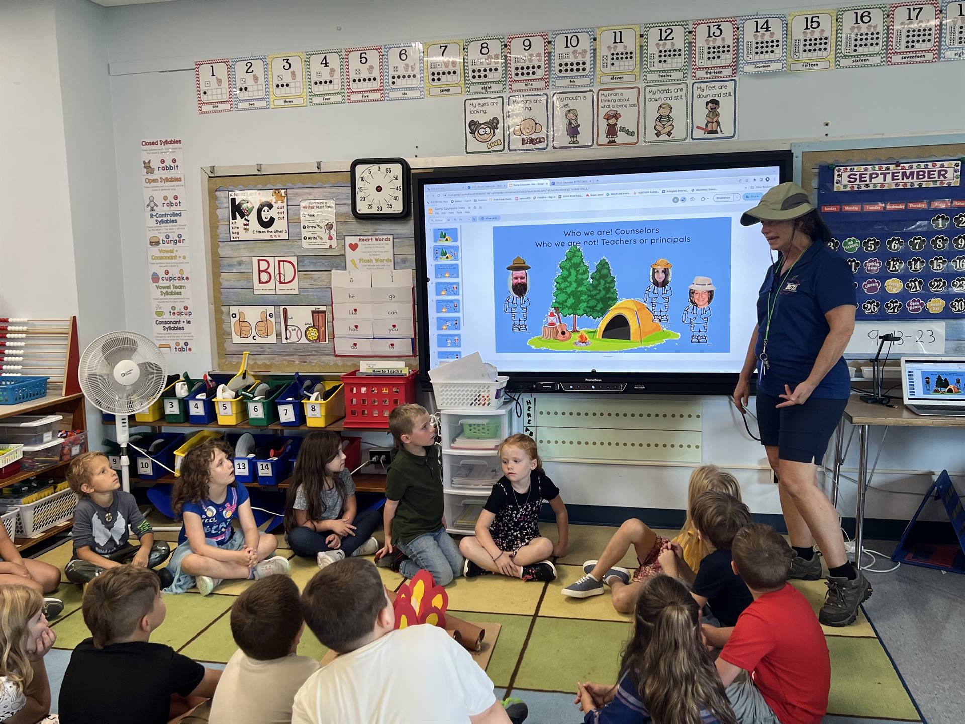 students looking at smart board and listening to adult dressed as a camper