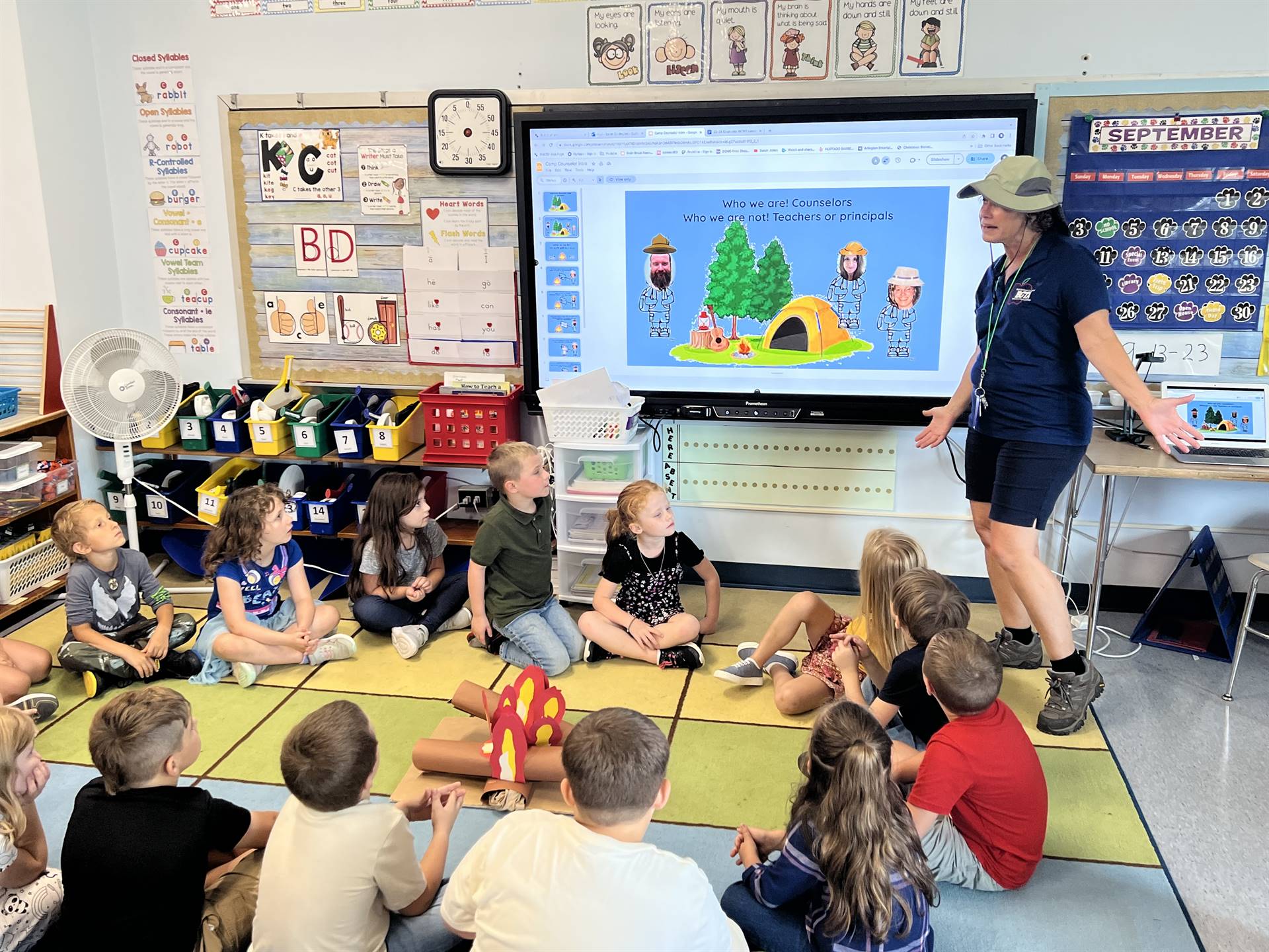 students looking at smart board and listening to adult dressed as a camper