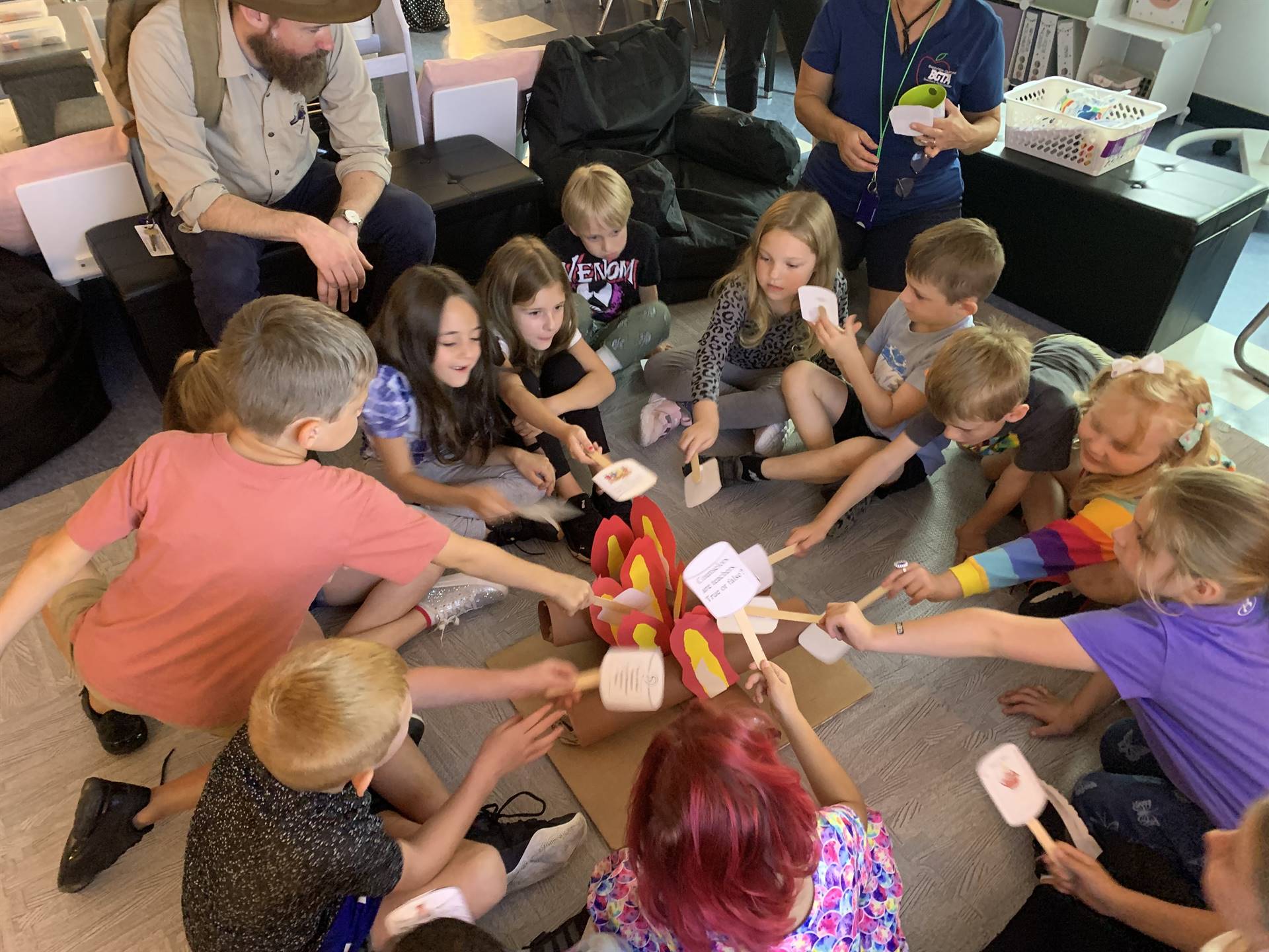 students sitting around a fake campfire roasting fake marshmallows