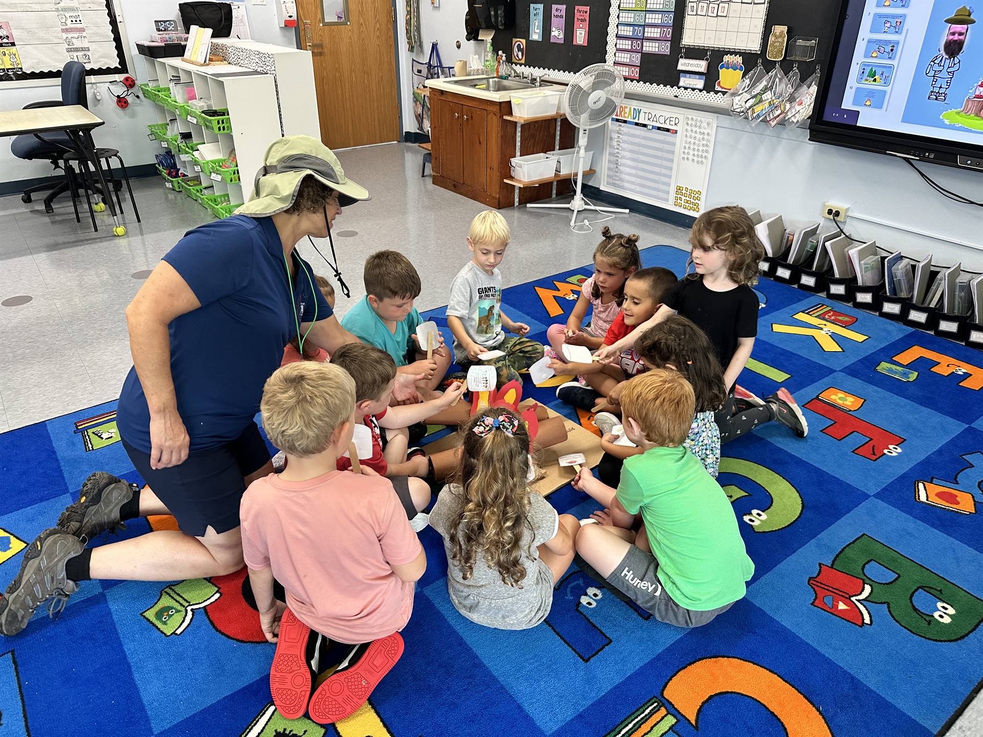 Counselor dressed as a camper roasting fake marshmallows with students.