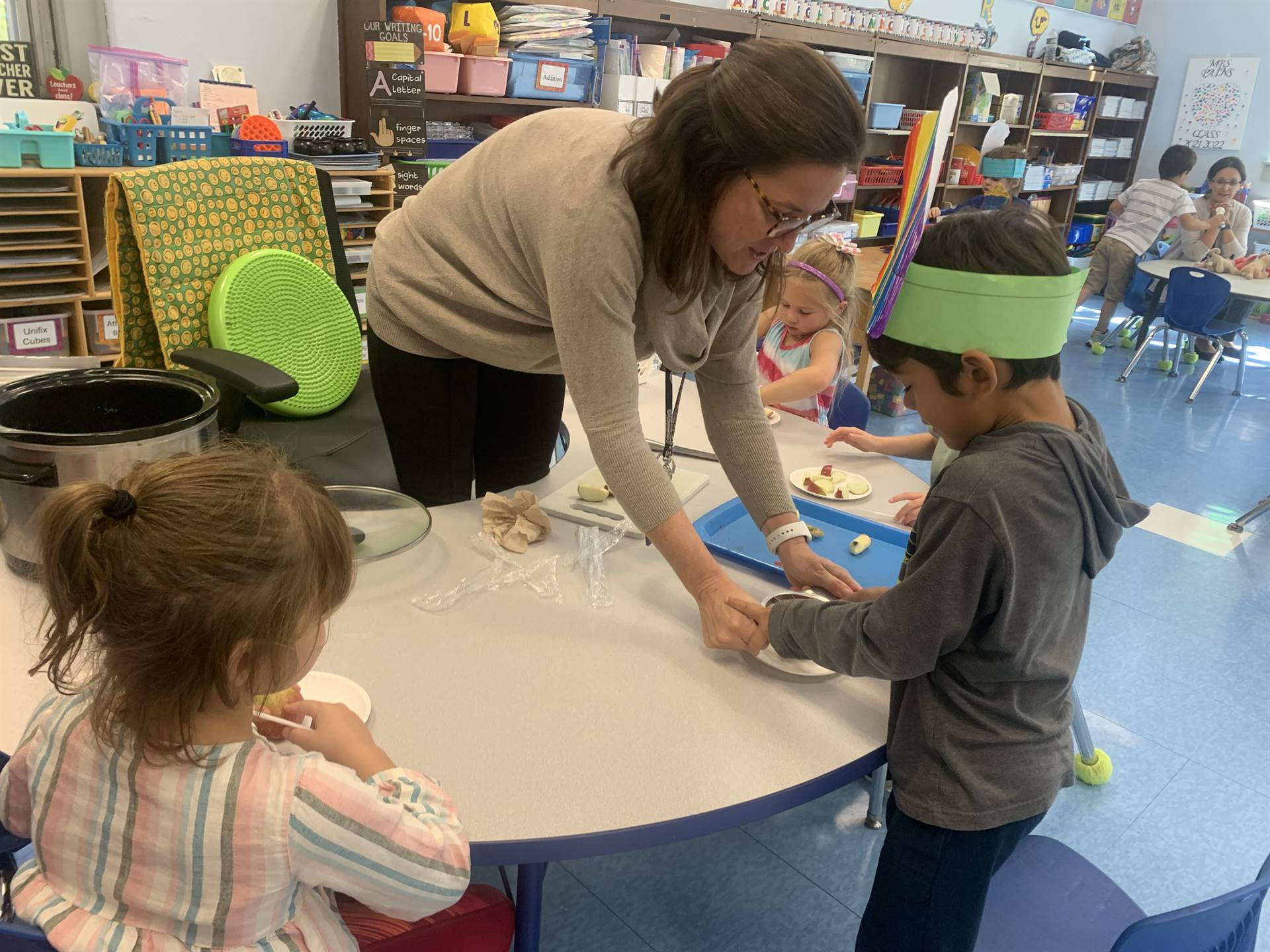 a teacher helps kids cut apples