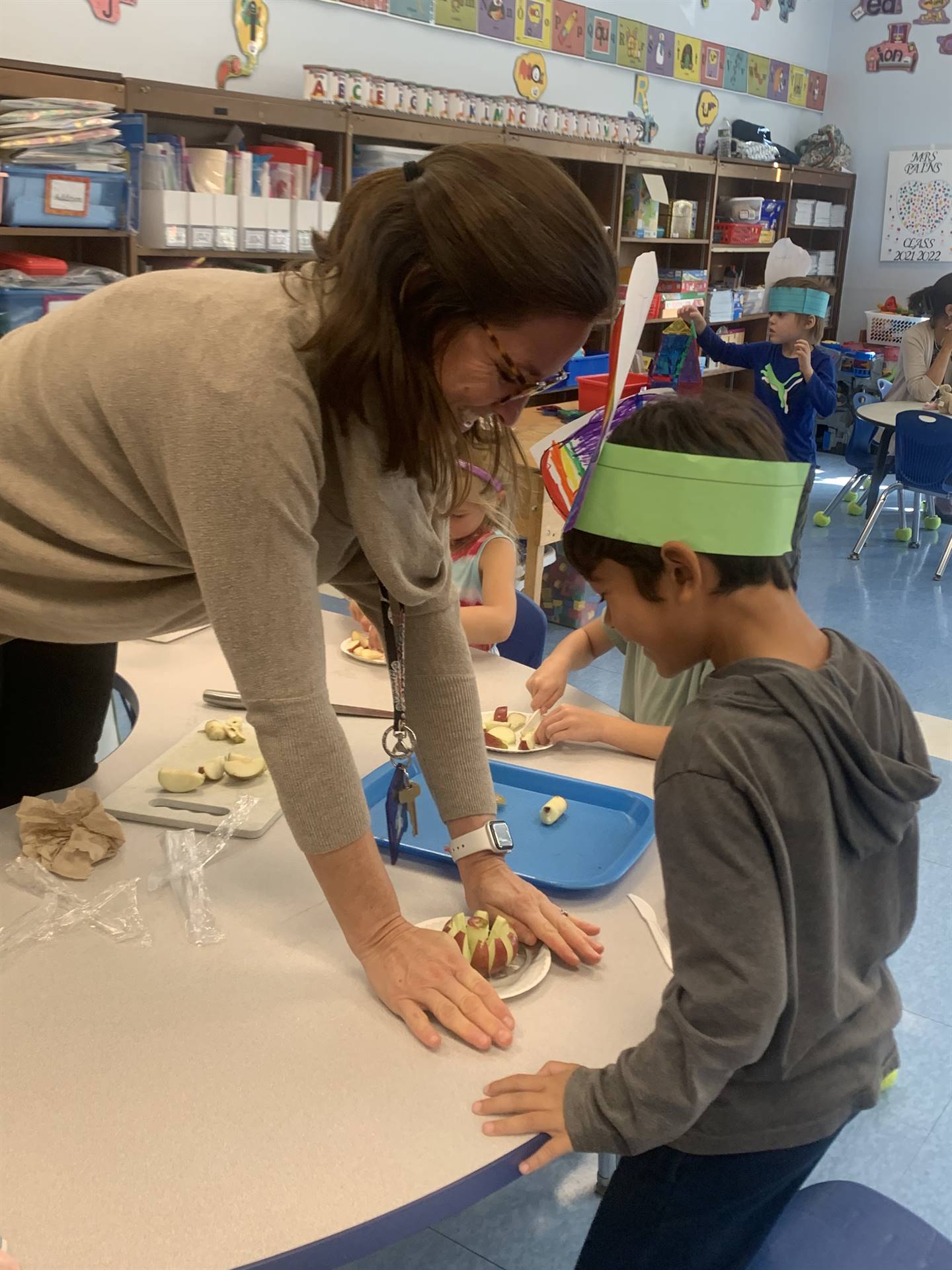 a teacher helps kids cut apples