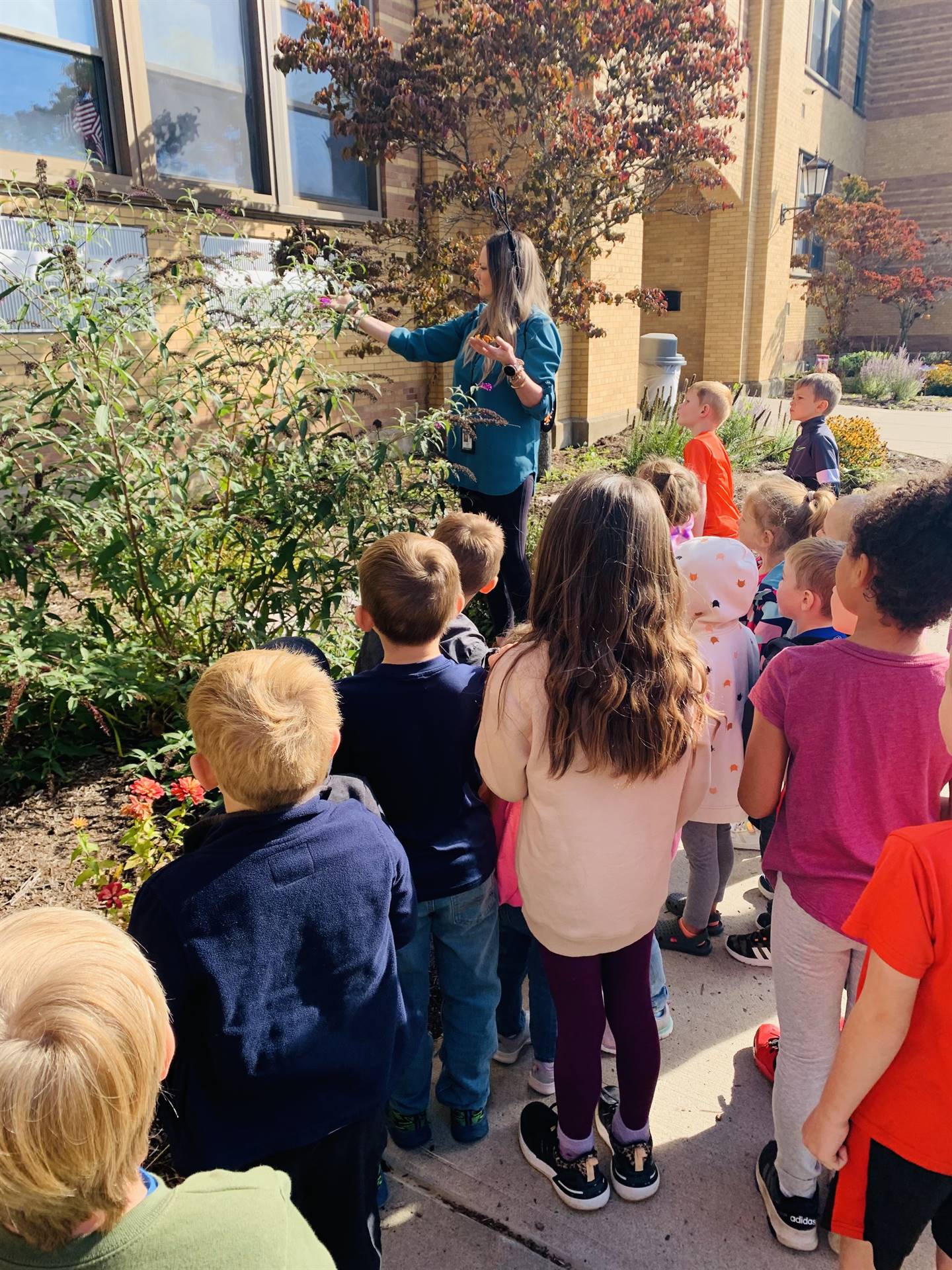 teacher pointing to a butterfly bush.