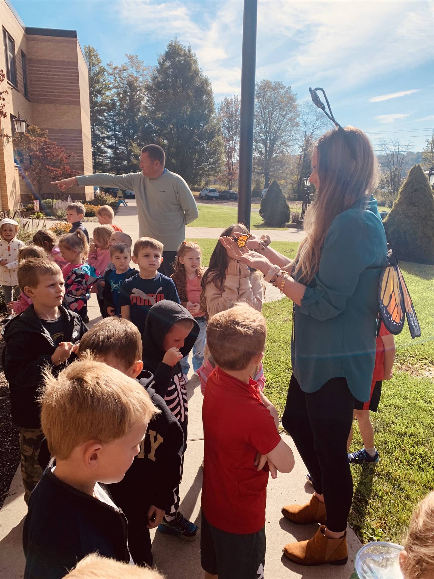 students and teacher watching monarch butterflies in teacher's hand.