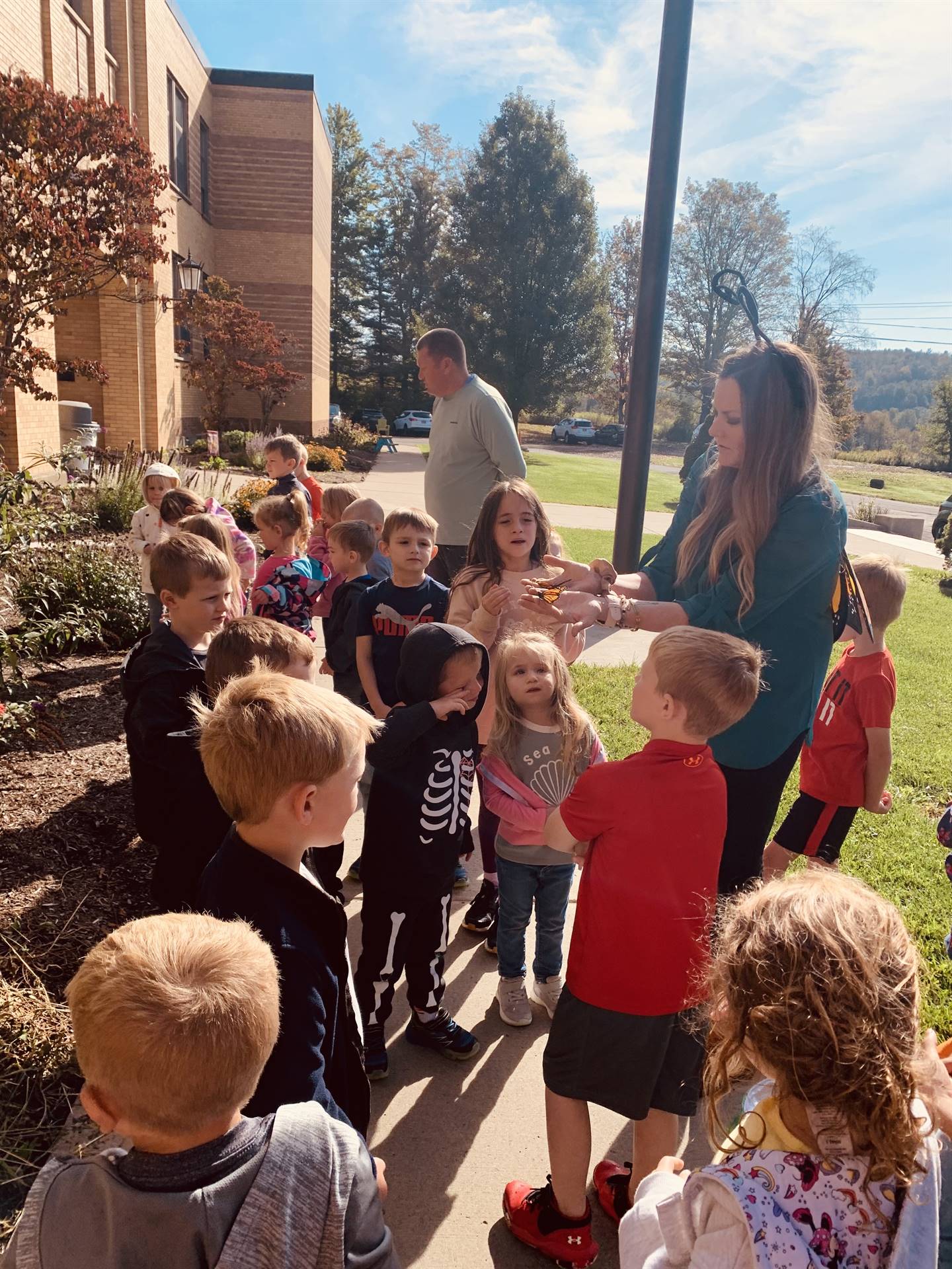 students and teacher watching monarch butterflies in teacher's hand.