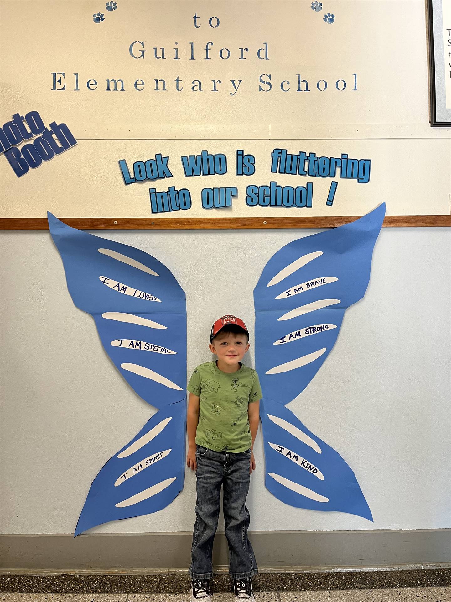 student standing between butterfly wings with sign on top saying "look who is fluttering into our sc