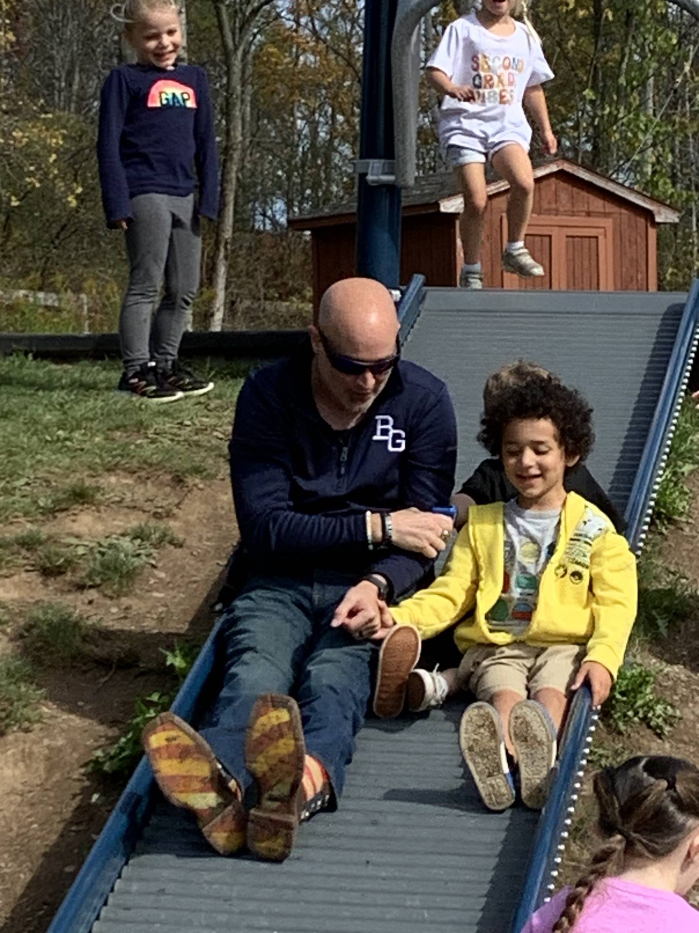 adult and student sliding down a slide.