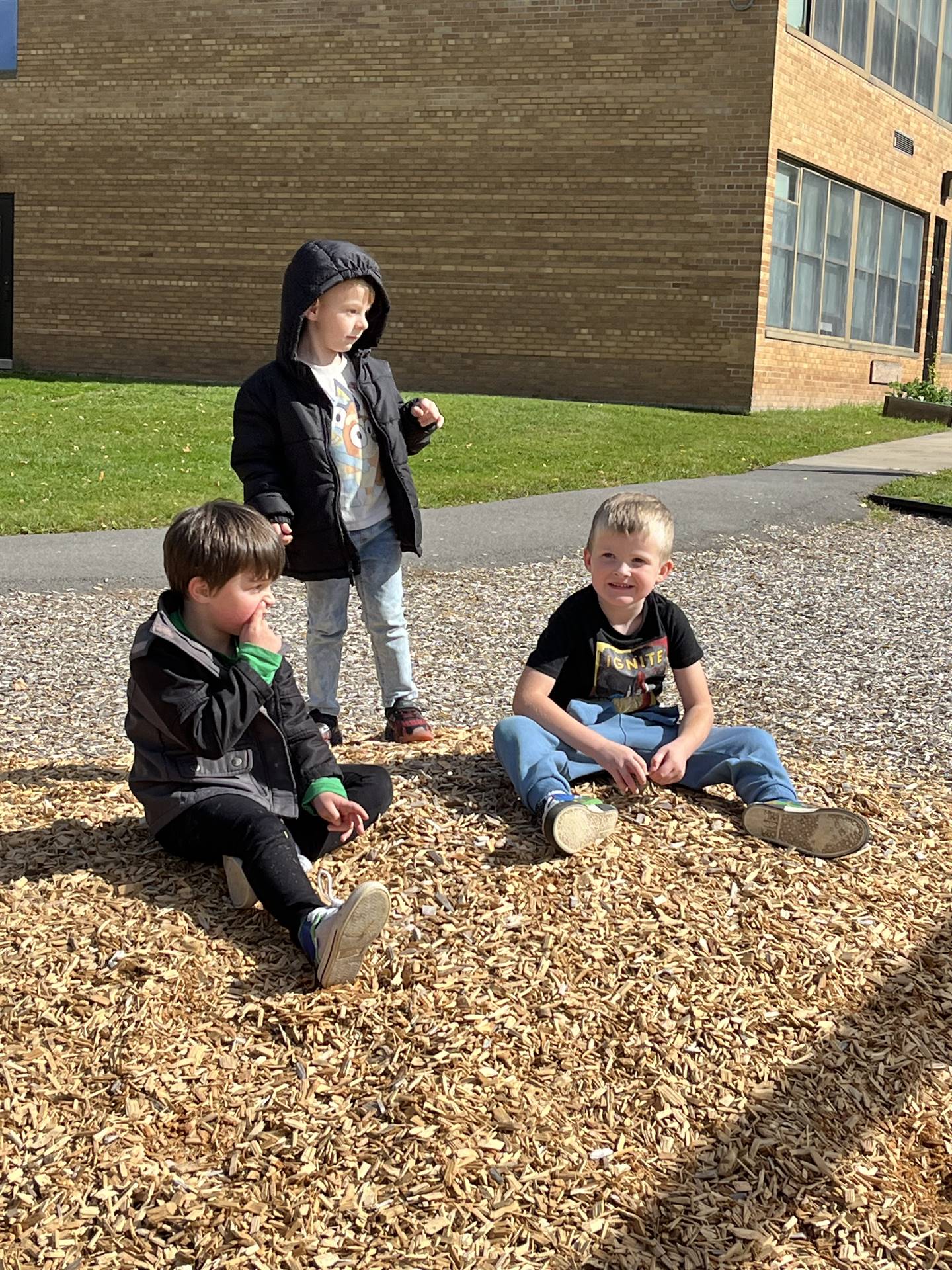 3 students on a bark chip pile