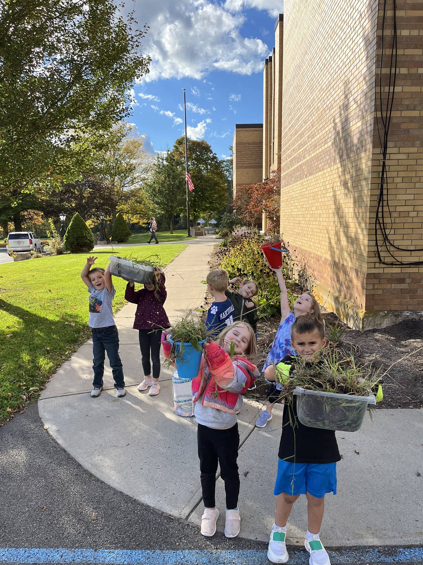 students carrying pails full of weeds.