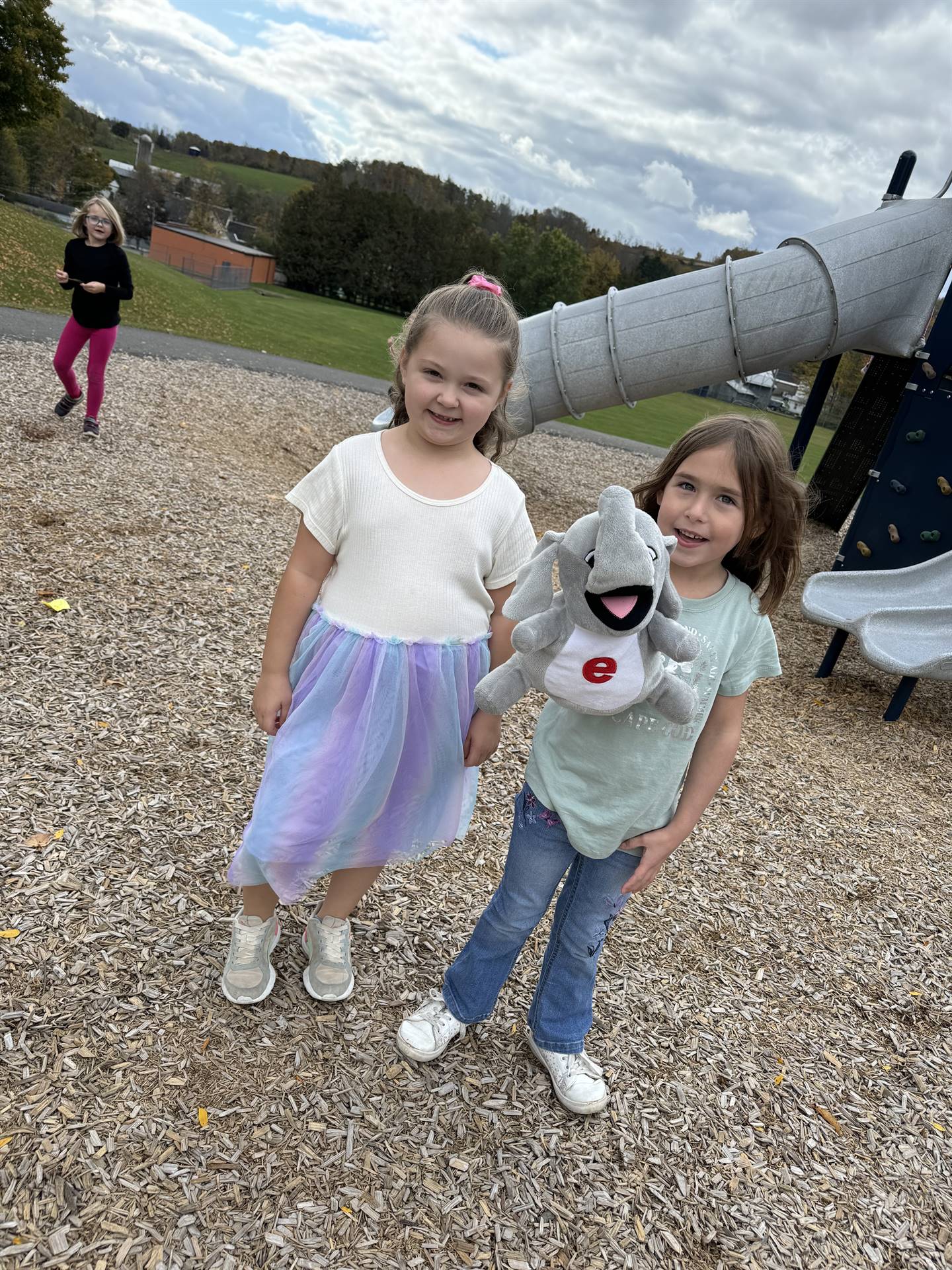 2 students holding an elephant puppet on the playground