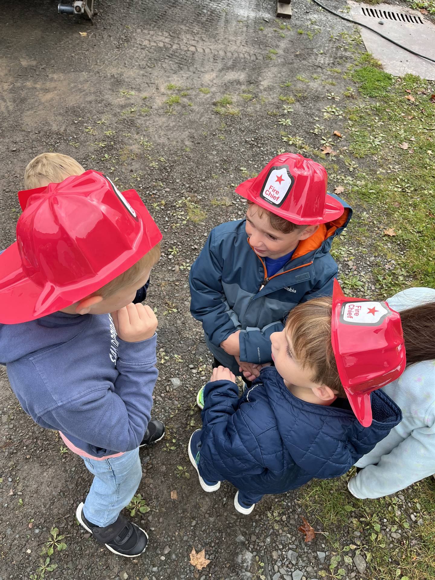 3 students with red fire hats discuss fire safety together