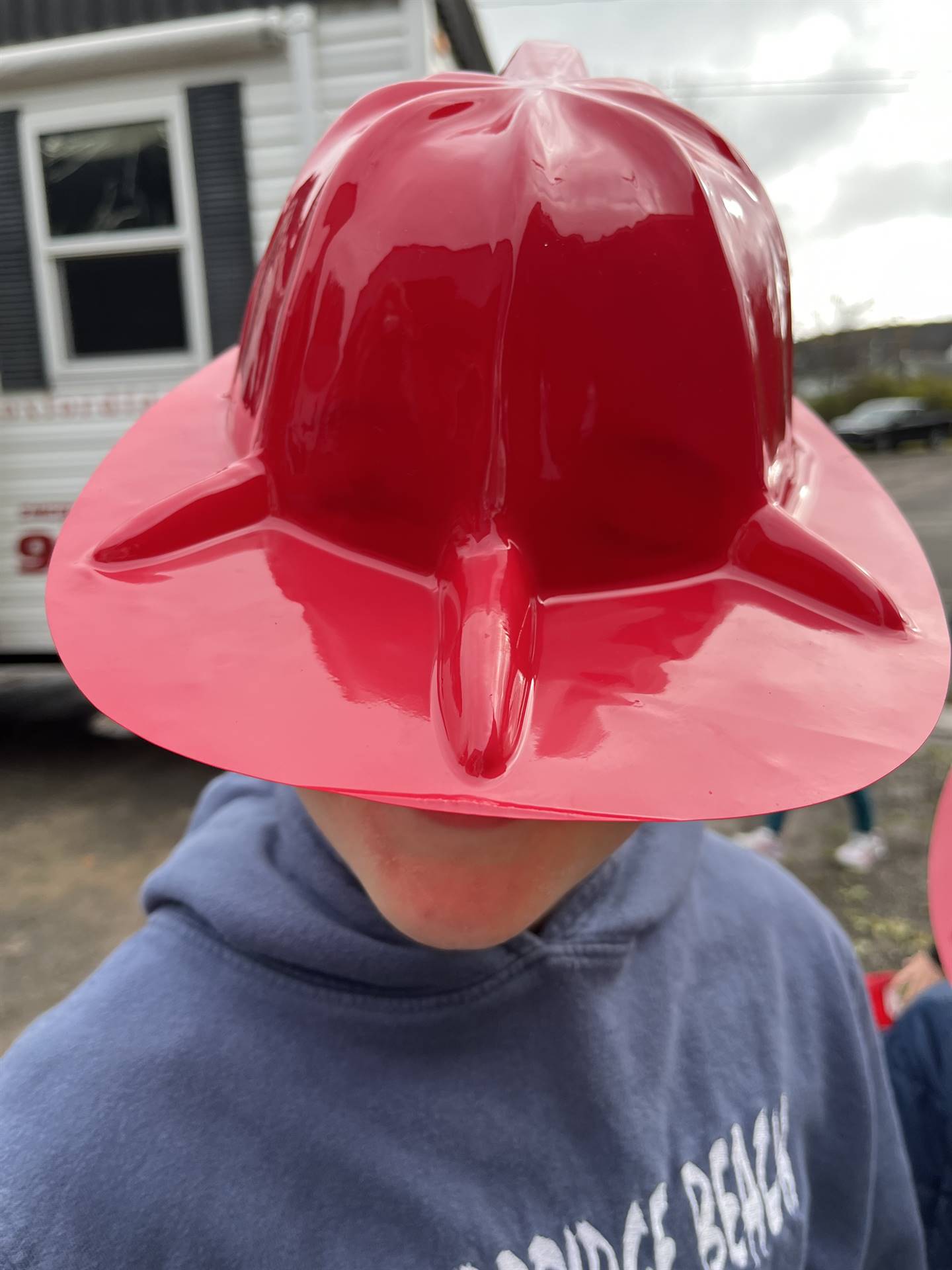 a student covers his face with a red fire helmet.