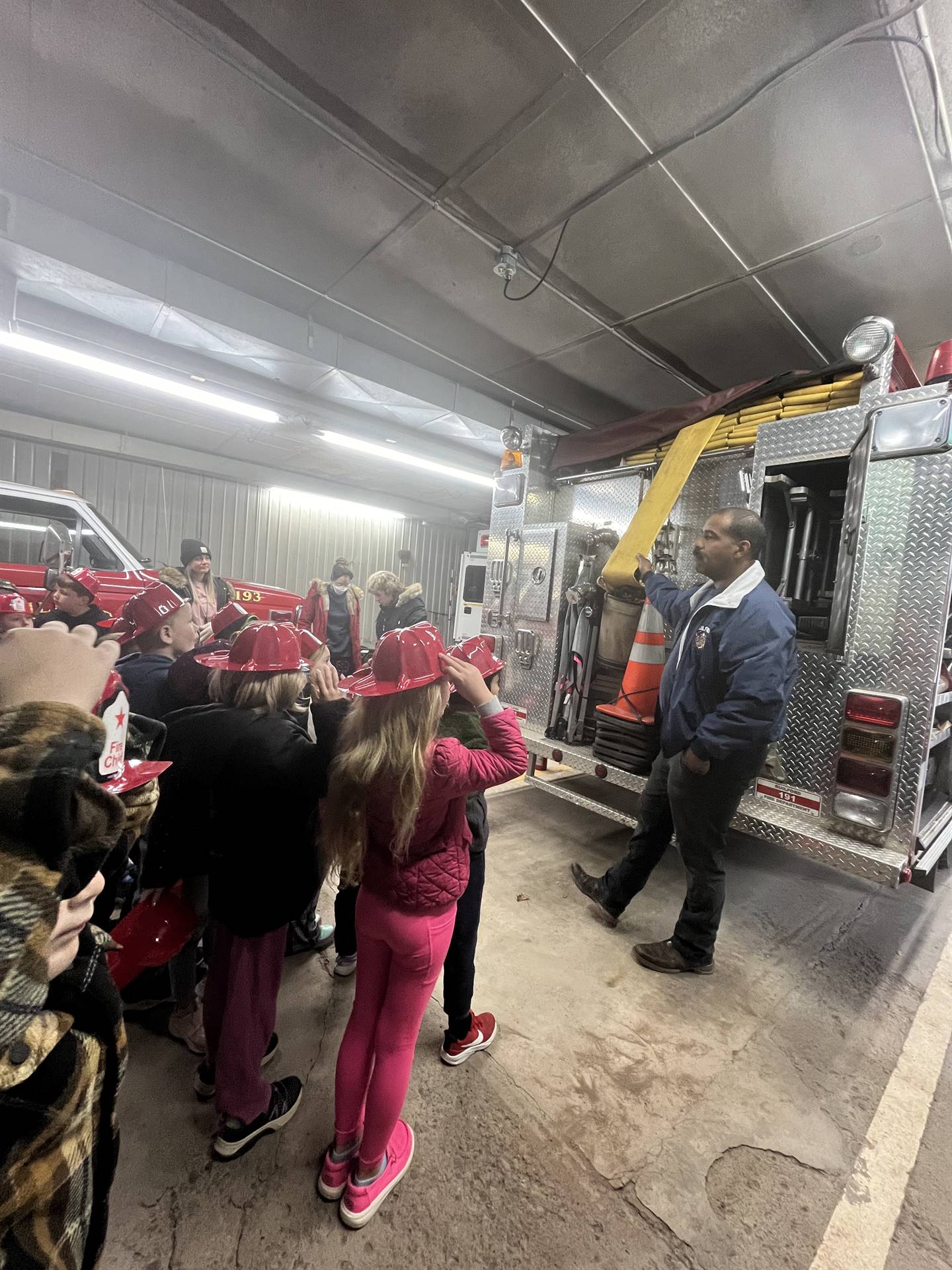 students standing inside firehouse listening to firefighters talk about the ambulance