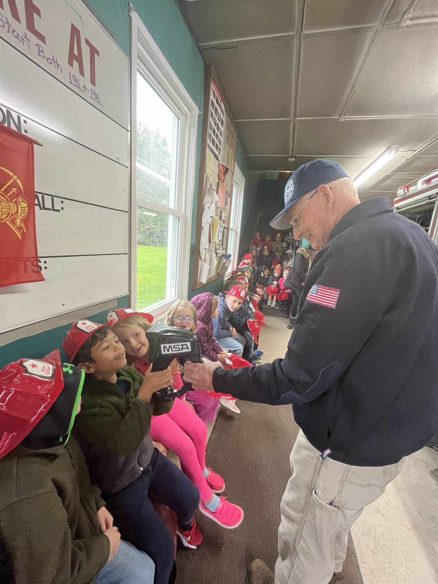 students look through an infrared camera while a fire fighter holds it.