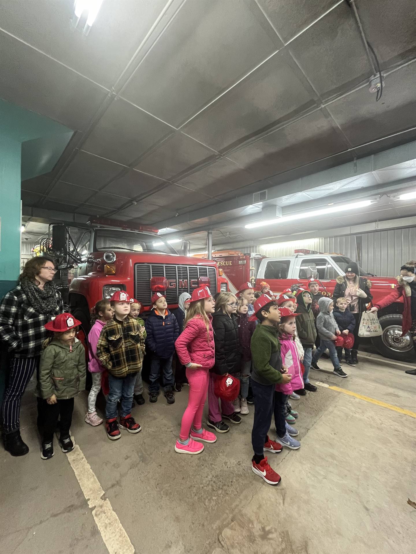 students standing inside firehouse listening to firefighters talk
